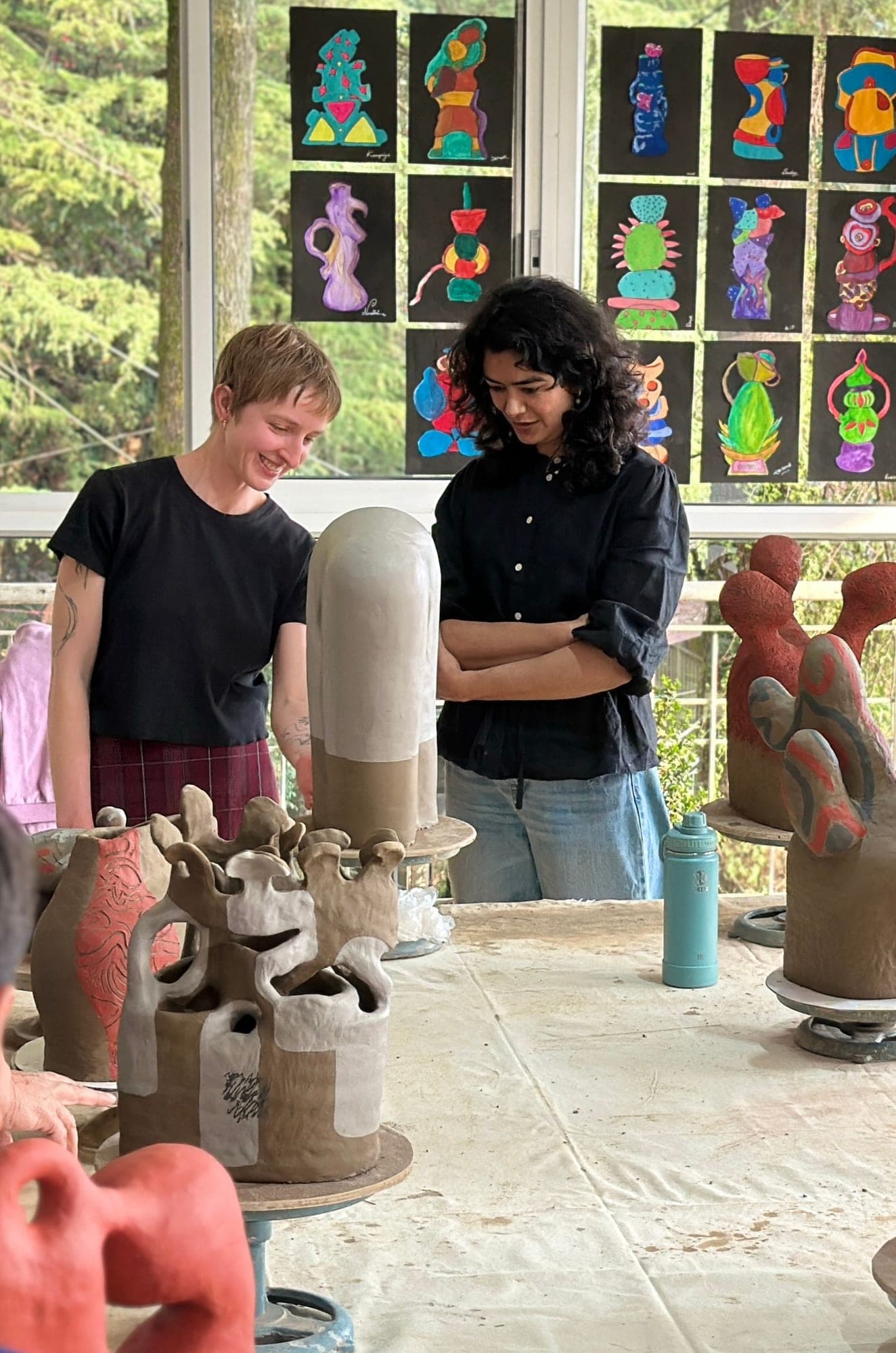 Artist residency participants reviewing sculptural pottery work at Dharamkot Studio.