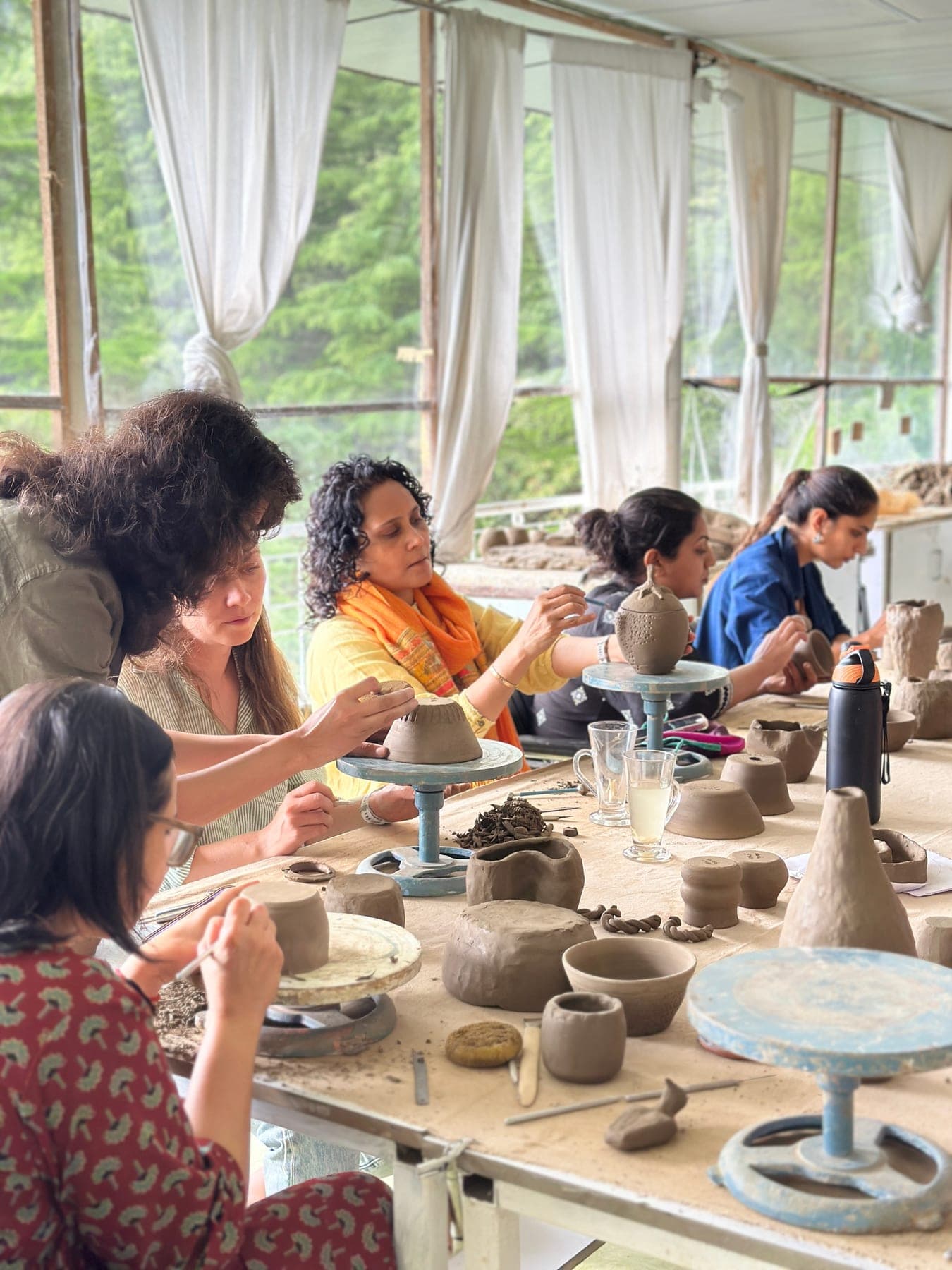 Pottery retreat participants shaping clay together at Dharamkot Studio.