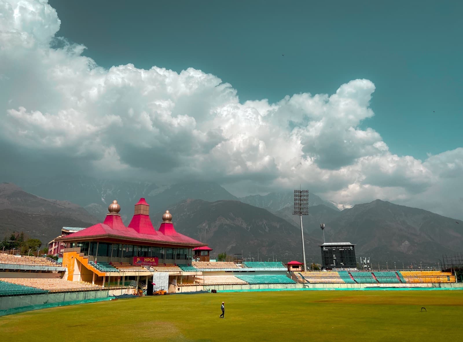 Dharamshala Cricket Stadium set against the Dhauladhar mountains.