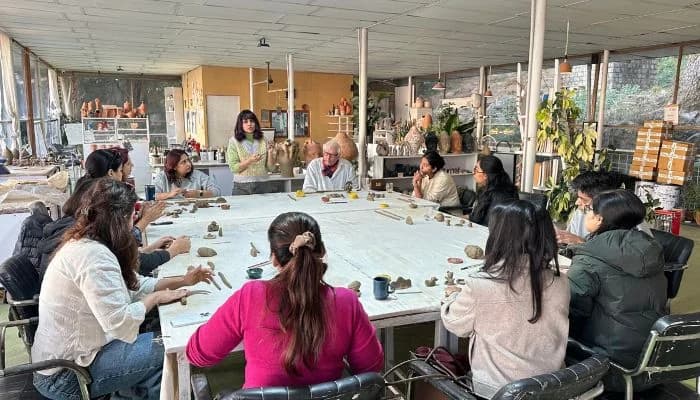 Participant sculpting detailed clay artwork during pottery retreat in India.