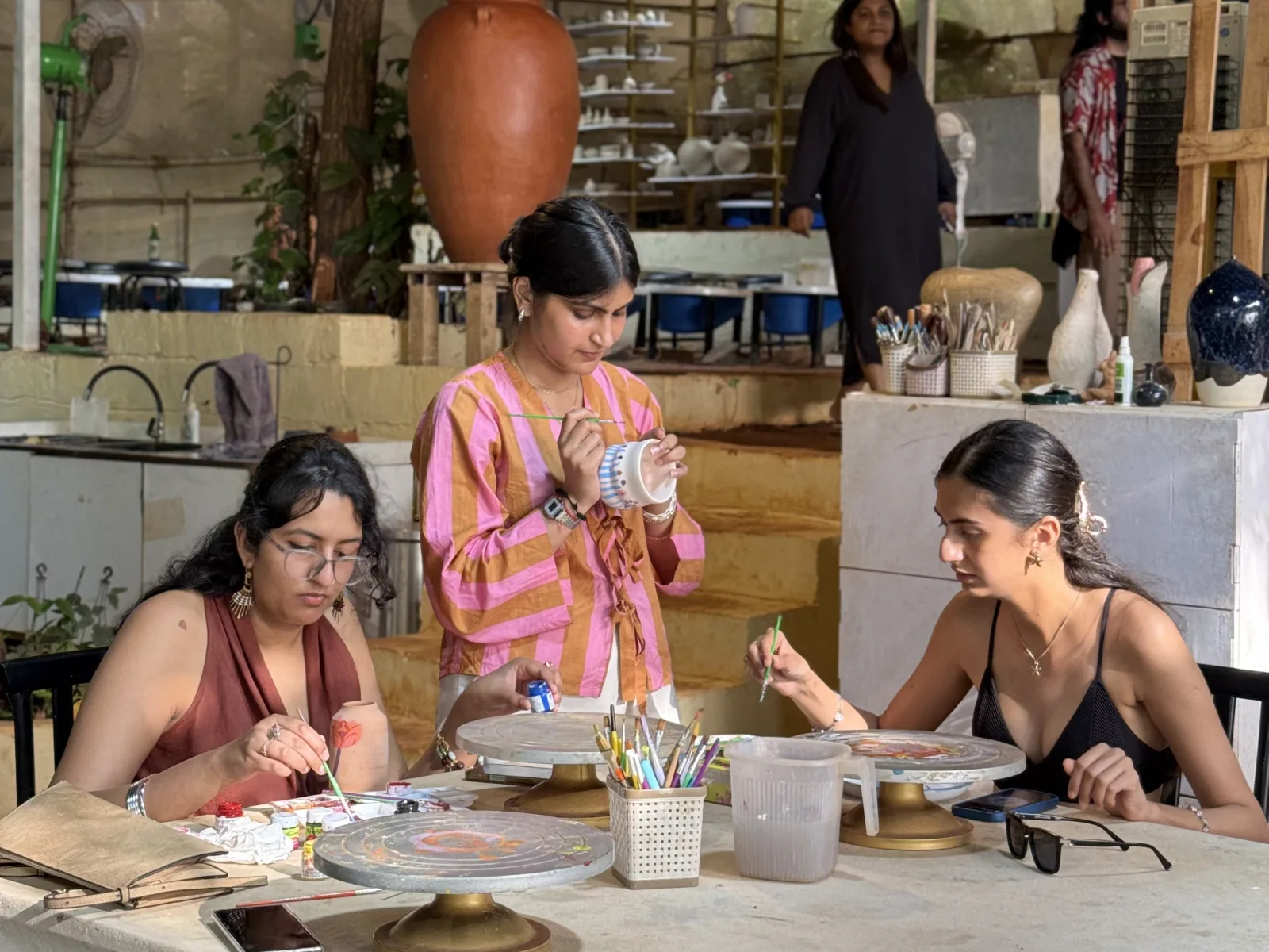 Participants decorating handmade ceramic pieces in the studio.