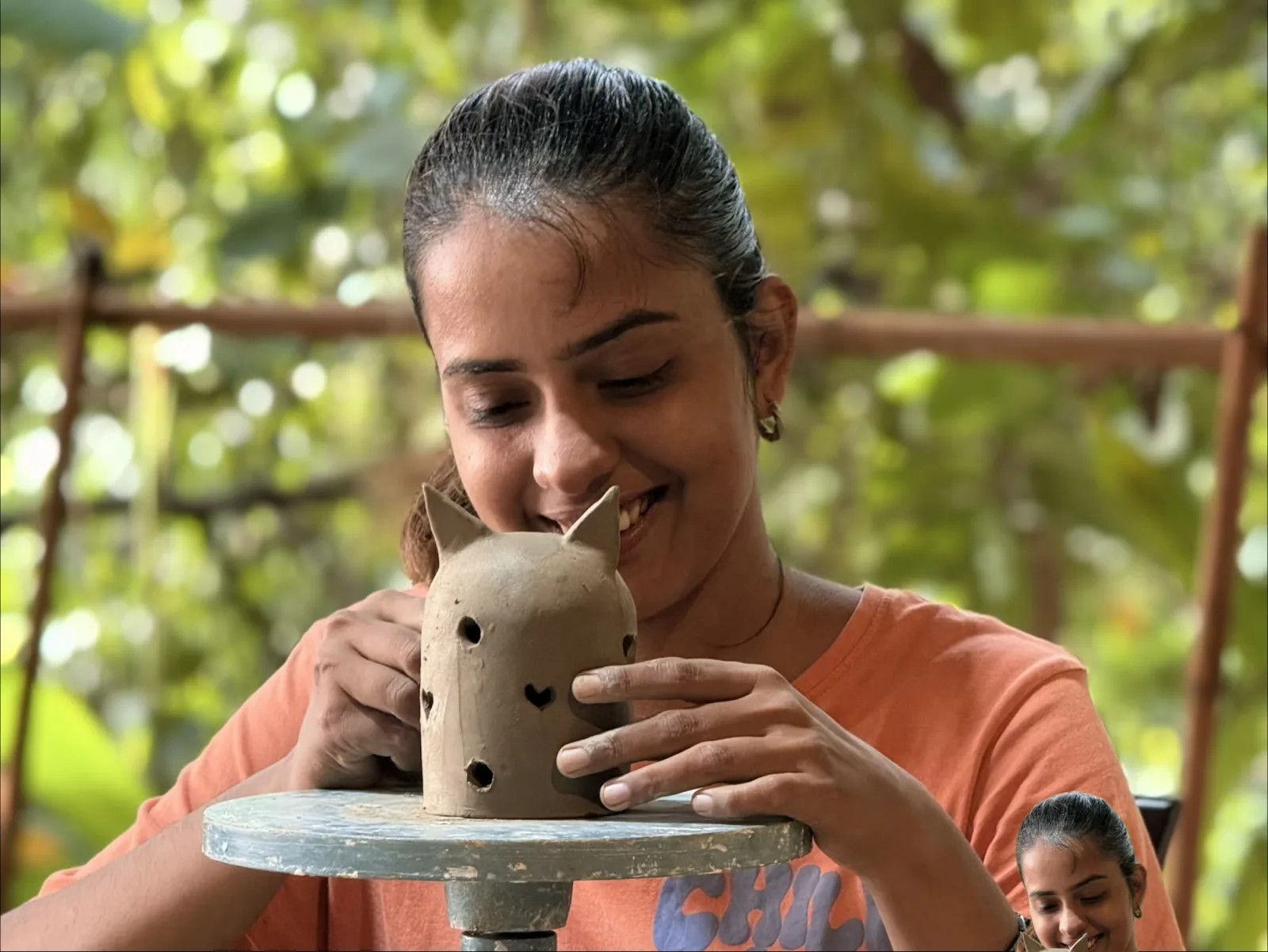 A ceramic student shaping a clay vessel by hand at Dharamkot Studio.