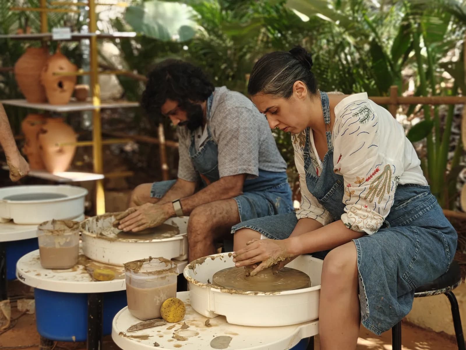 Two participants practicing on pottery wheels at Dharamkot Studio.
