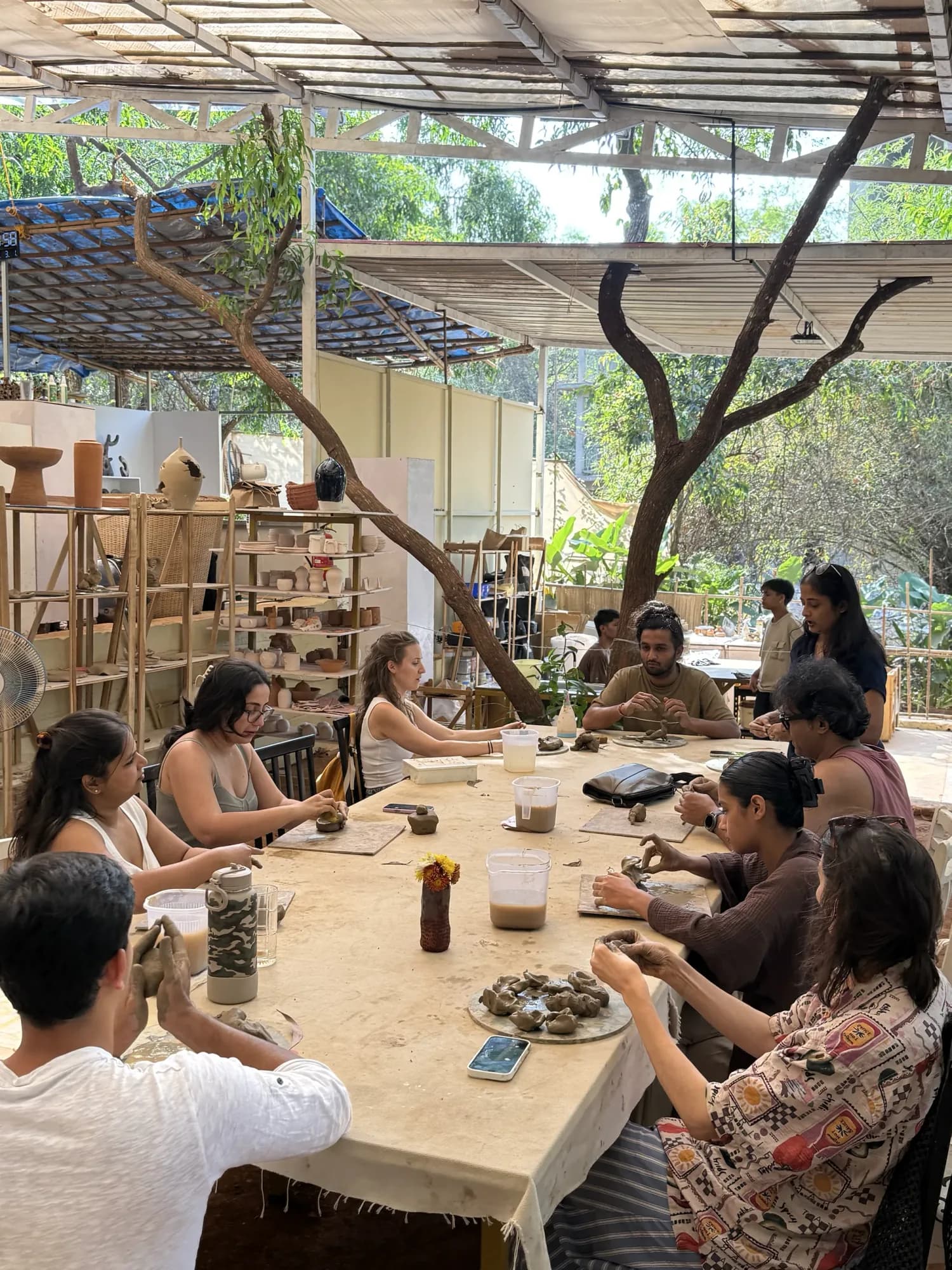 A long pottery table session inside Dharamkot Studio Goa with students working on clay forms.