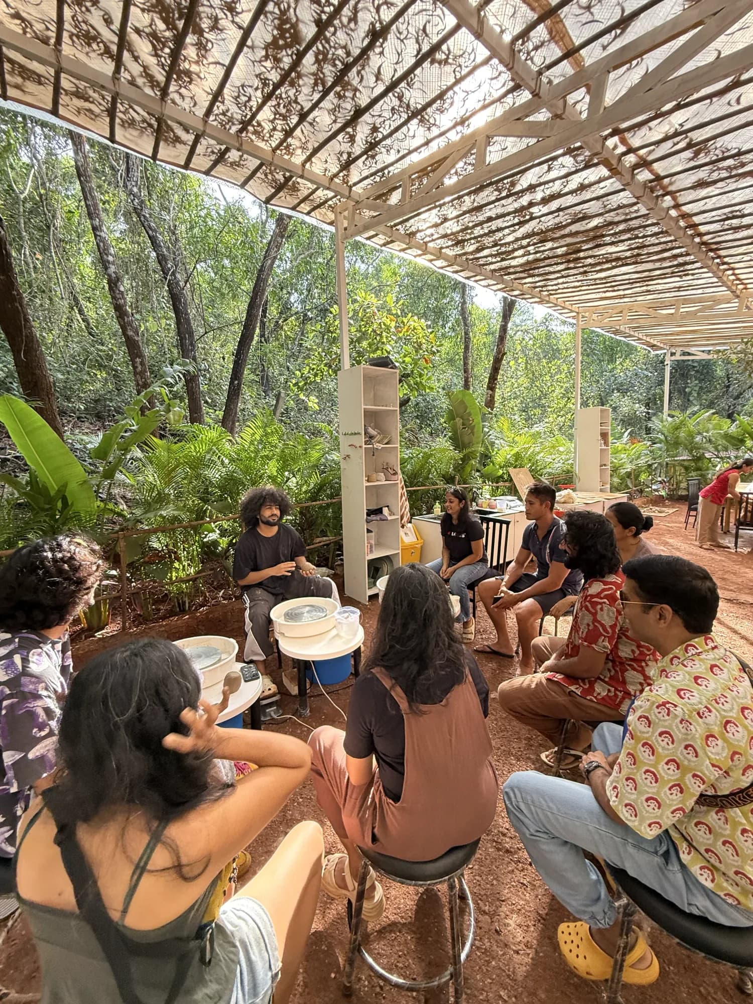 Students gathered for a pottery session in the open-air Dharamkot Studio Goa space surrounded by cashew trees.