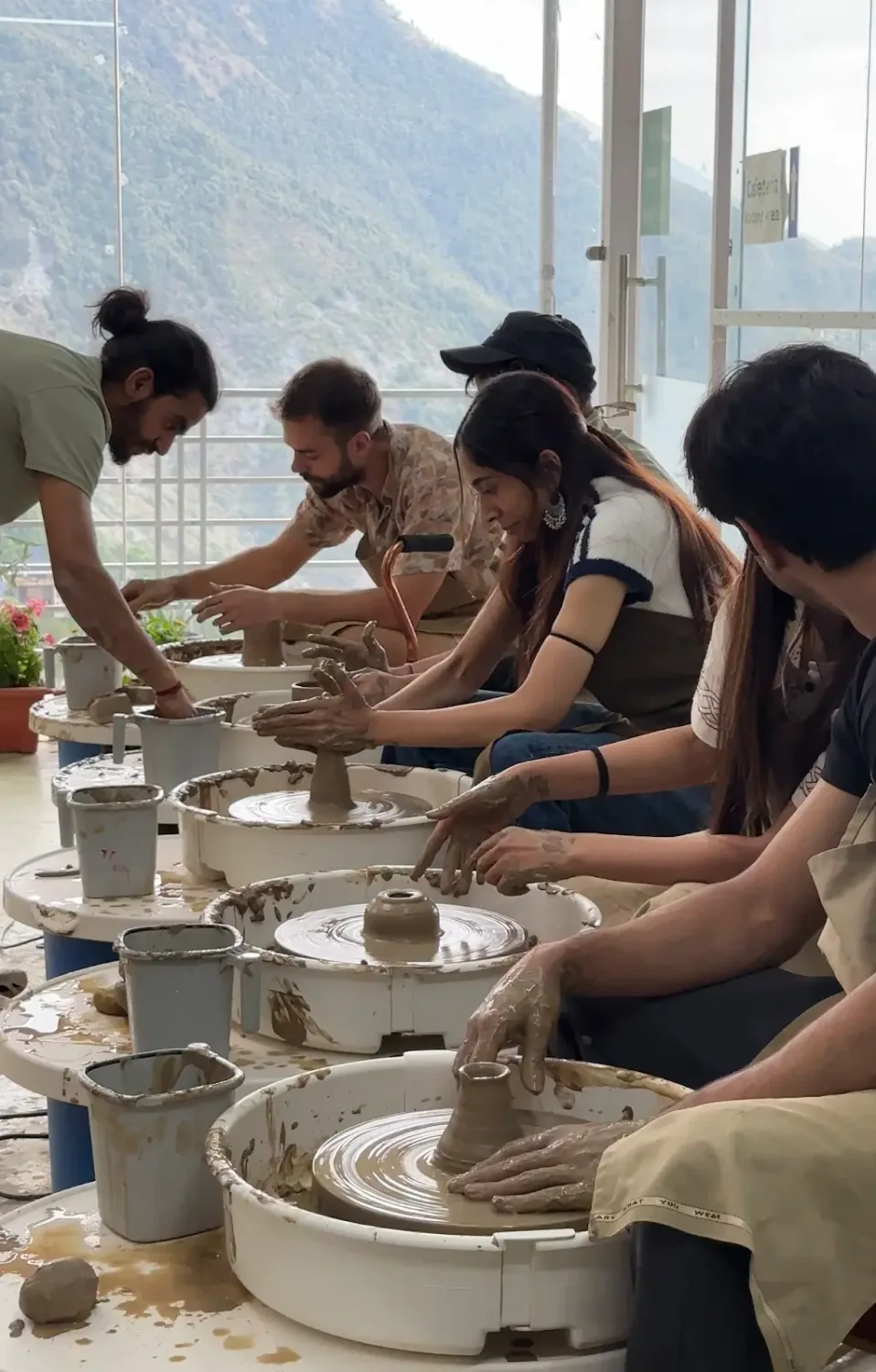 Students and visitors making pottery inside Dharamkot Studio's community art space.