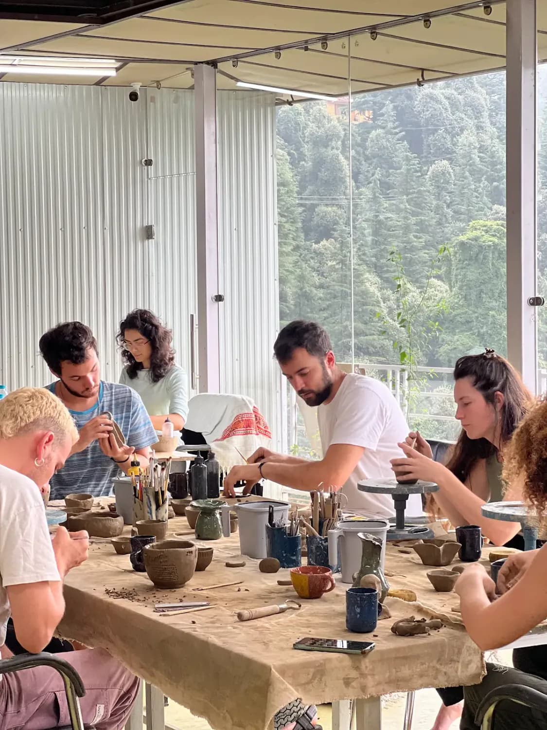 Students and visitors making pottery inside Dharamkot Studio's community art space.