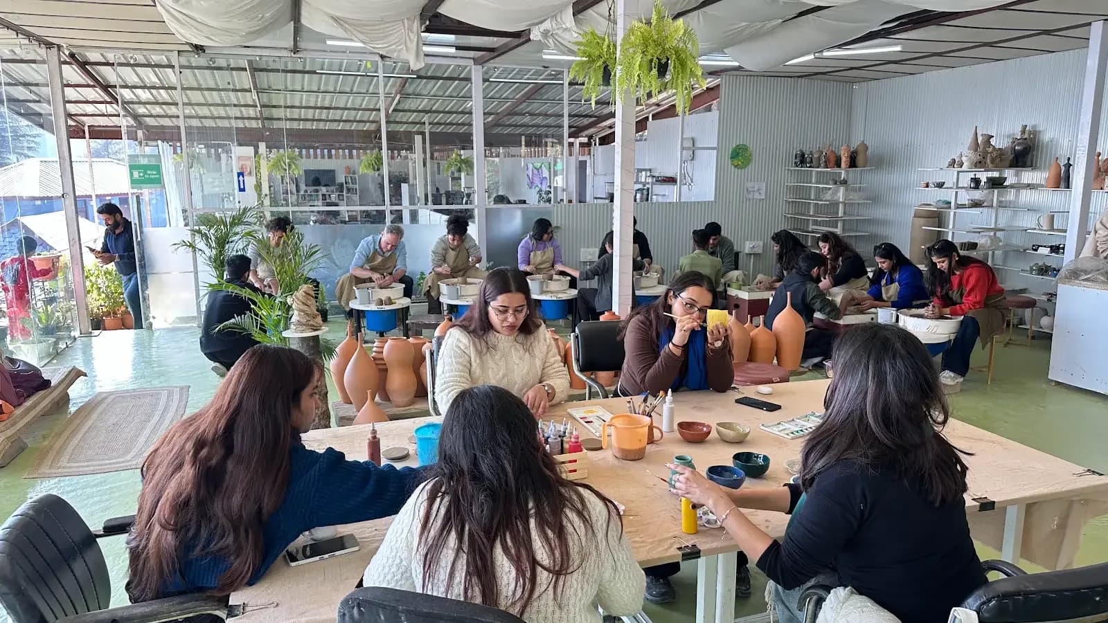 Students and visitors making pottery inside Dharamkot Studio's community art space.