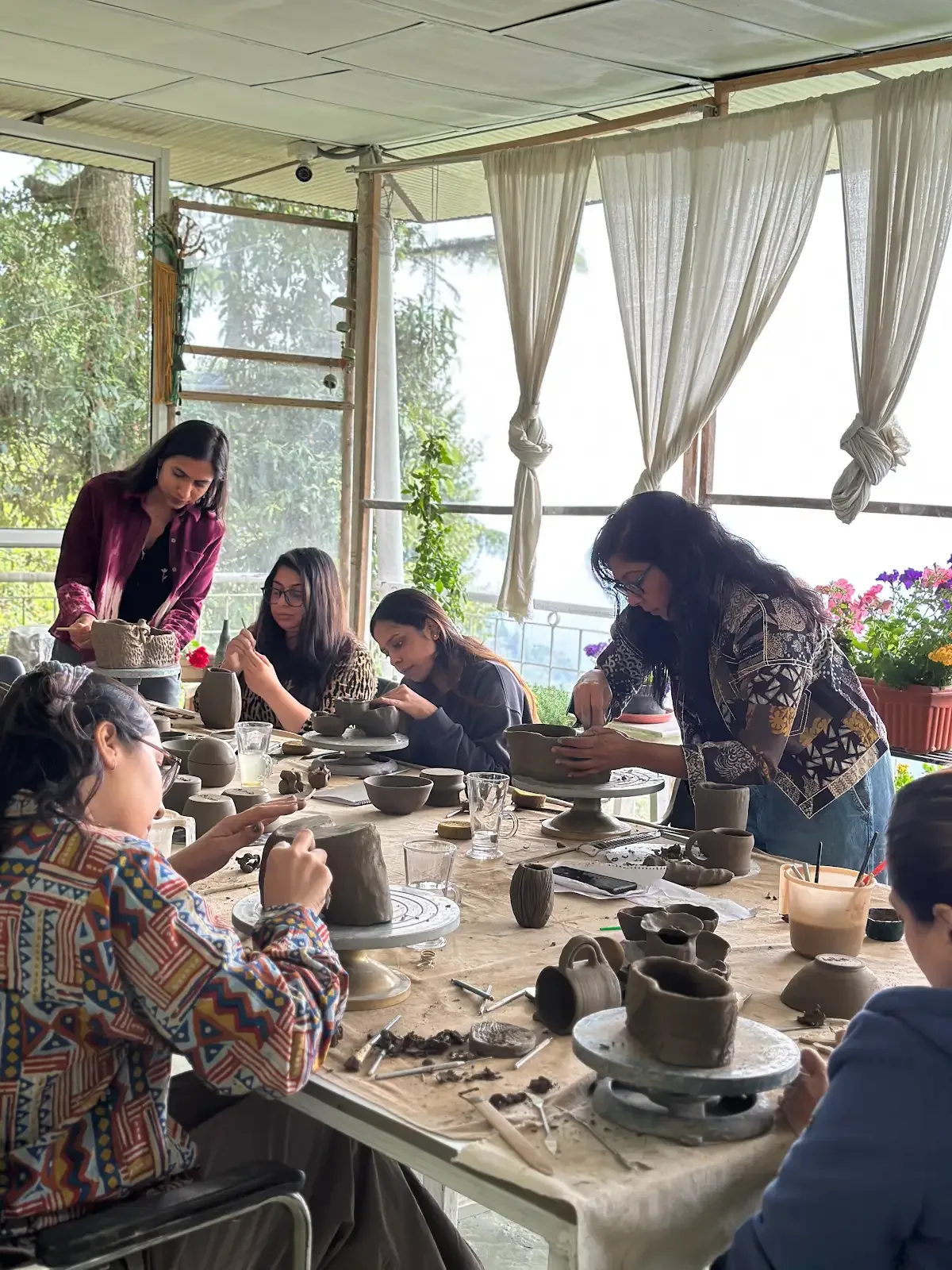Participants shaping clay together during a Himachal pottery retreat at Dharamkot Studio.