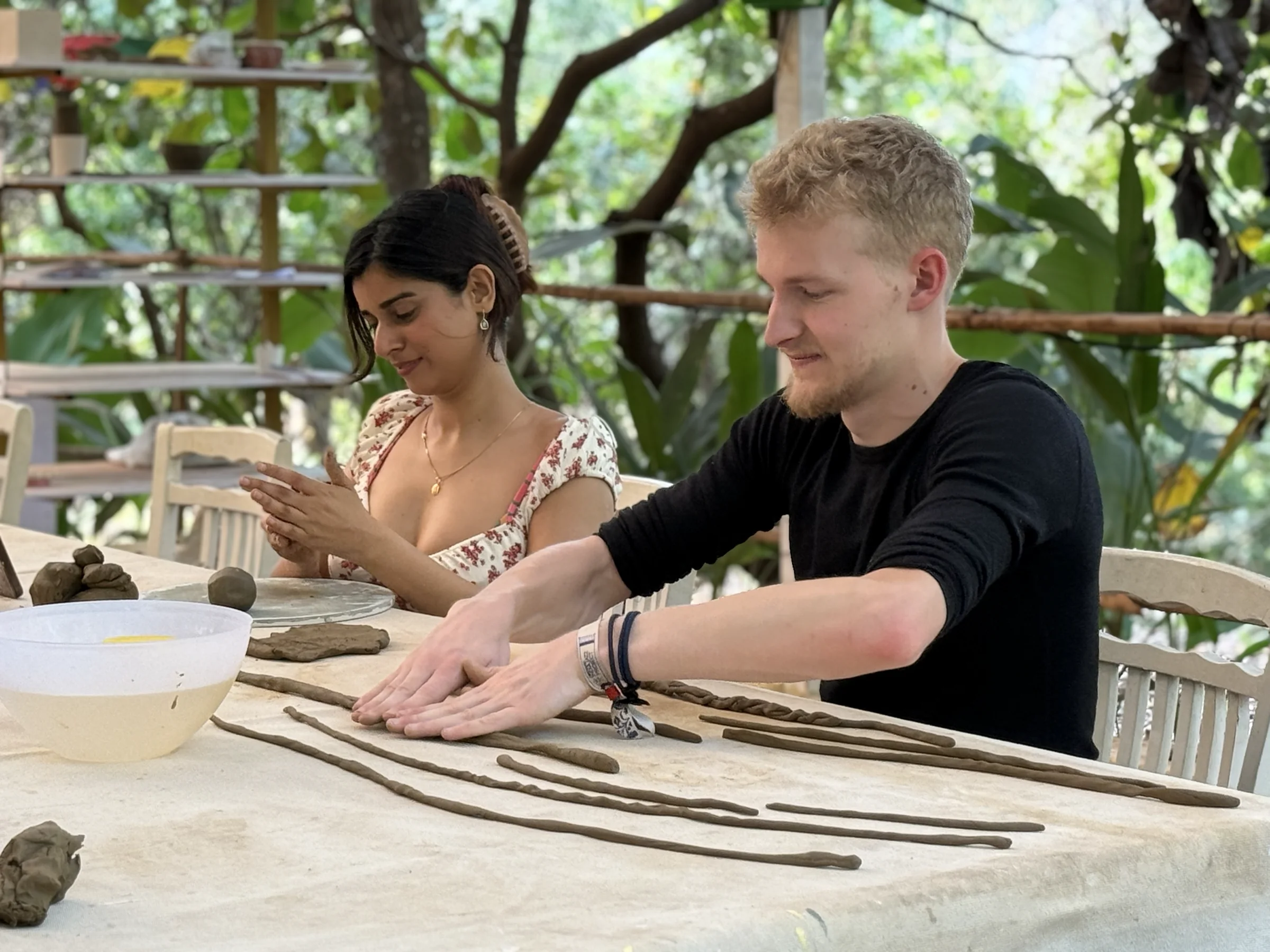 Retreat participants building clay forms together at a shared worktable in Goa.