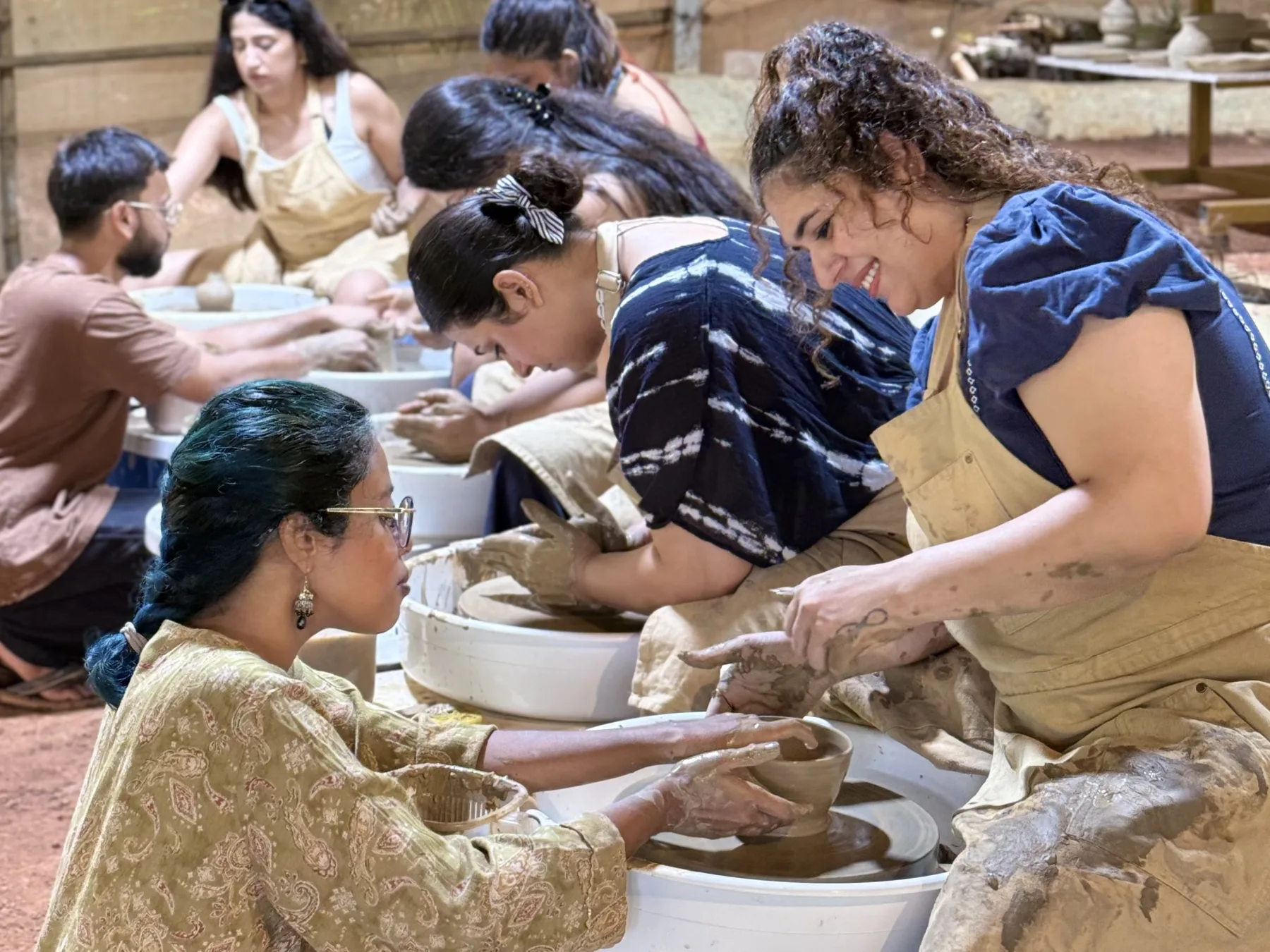 A pottery facilitator guiding retreat participants as they shape clay together on wheels in the Goa studio.