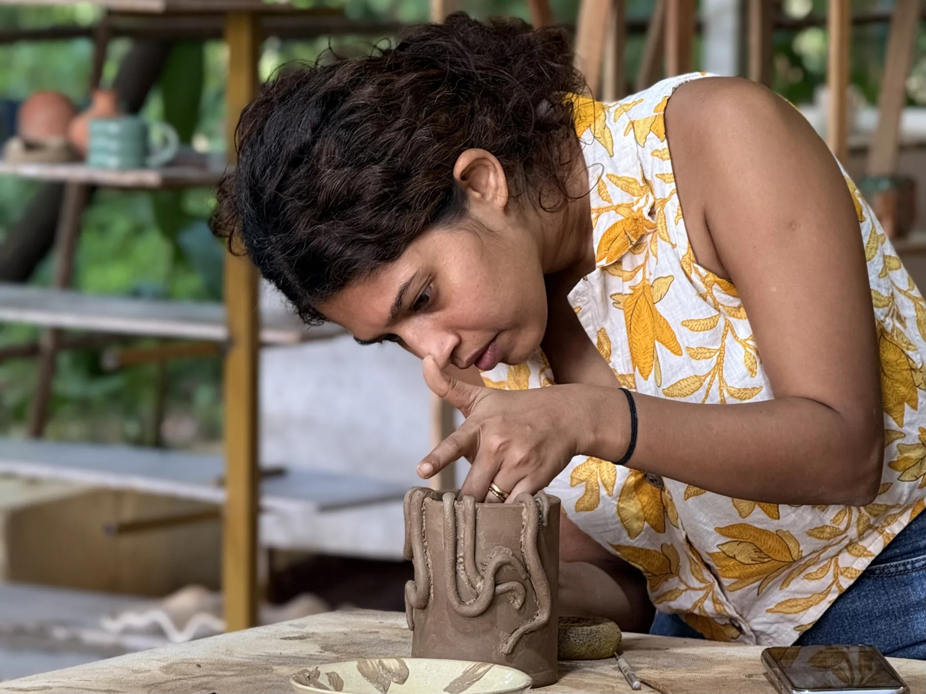 A participant adding raised clay decoration to a hand-built vessel during the Goa pottery retreat.
