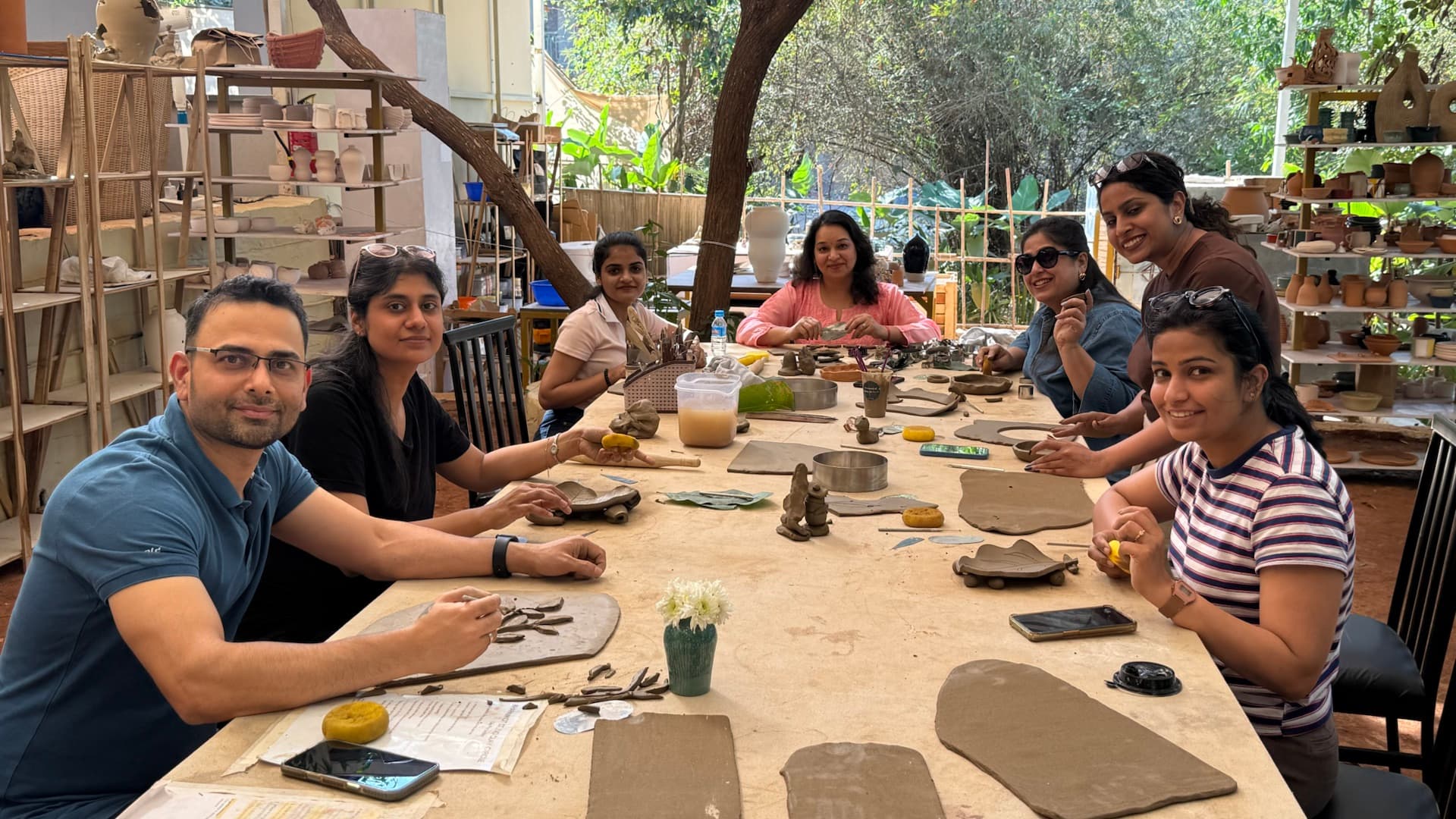 A group pottery practice session with participants seated around a studio table in Goa.