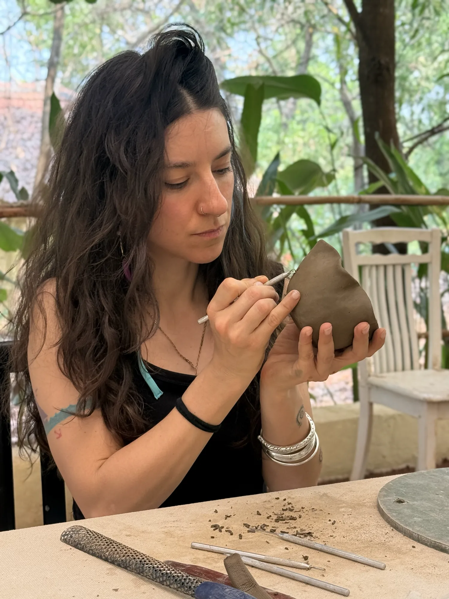 Participant carving the rim of a hand-built clay bowl during an open clay session at Dharamkot Studio in Goa.