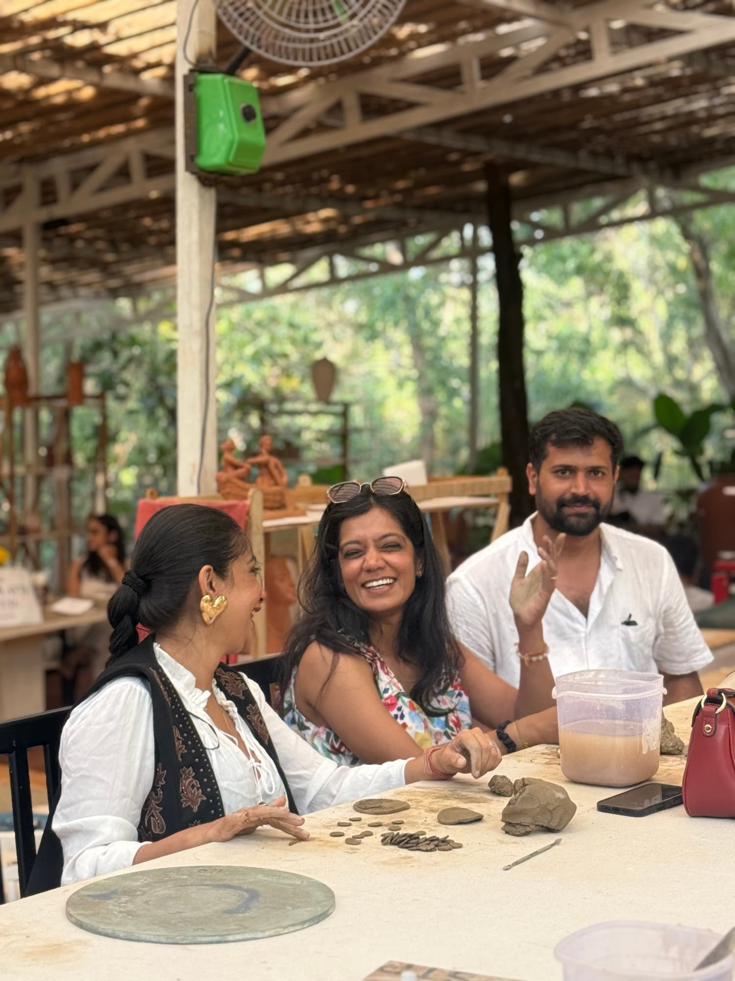 Participants smiling and making small clay pieces together during the Goa Open Clay Session.
