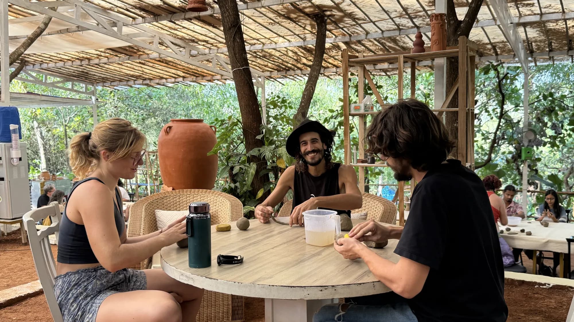 Friends making clay pieces together around a round table during Dharamkot Studio's Open Clay Session in Goa.