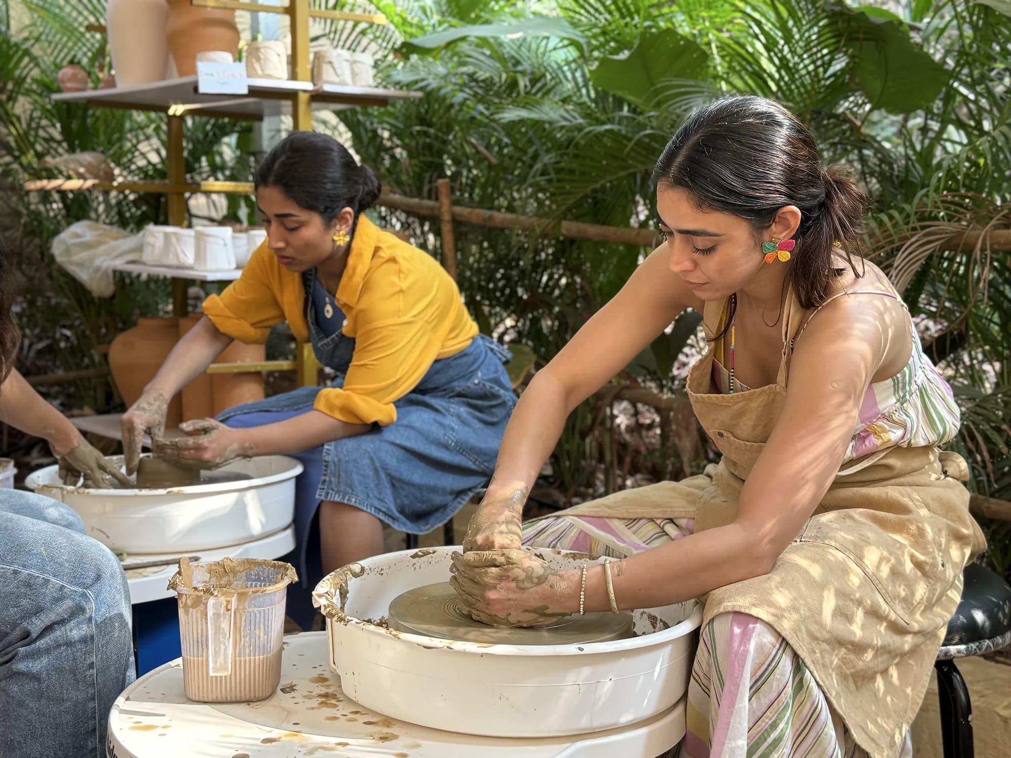 Two participants learning basic pottery wheel technique at Dharamkot Studio in Goa.