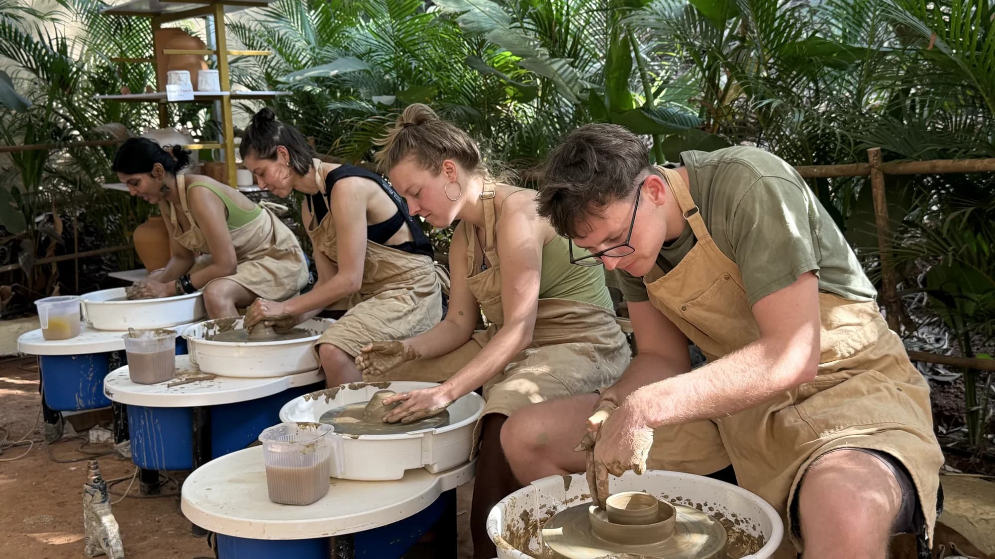 A close studio view of participants shaping clay on pottery wheels in Goa.