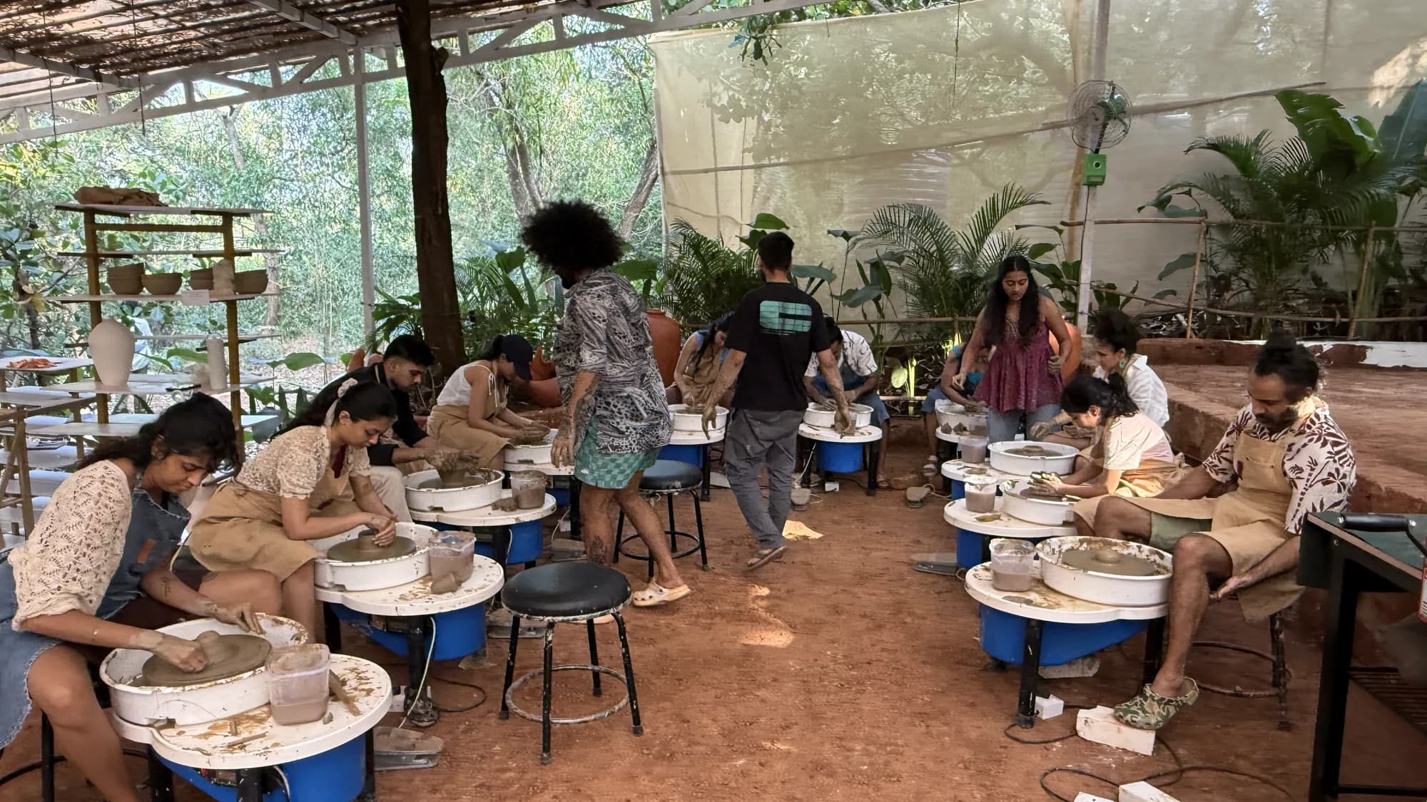 An open-air group pottery wheel class underway at Dharamkot Studio in Goa.