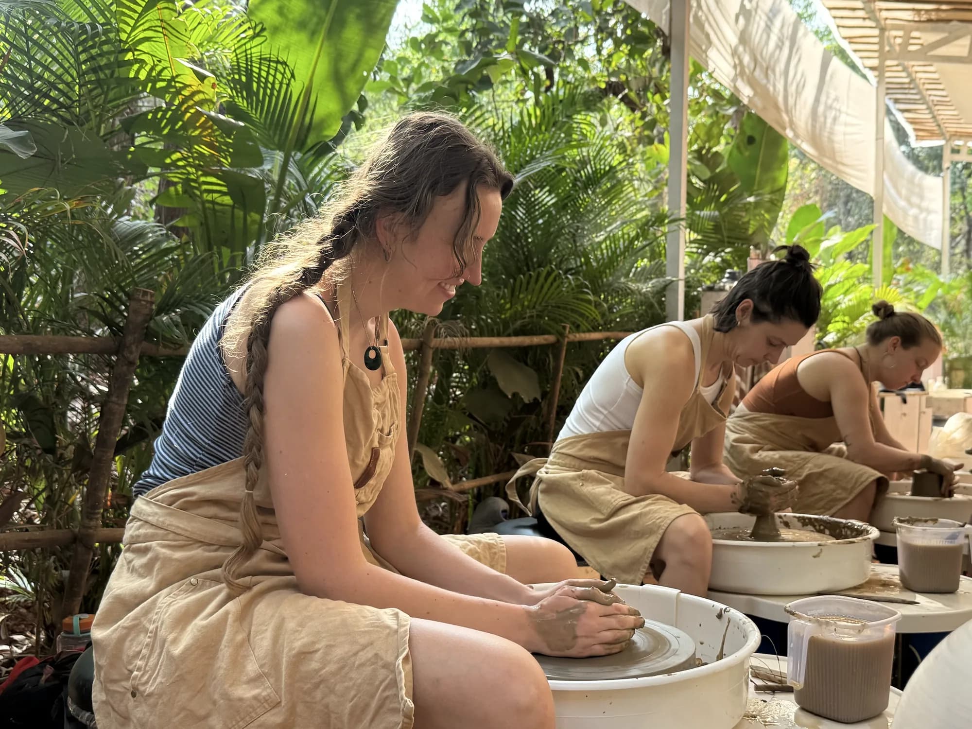 A workshop participant focusing on centering clay during a pottery wheel session in Goa.