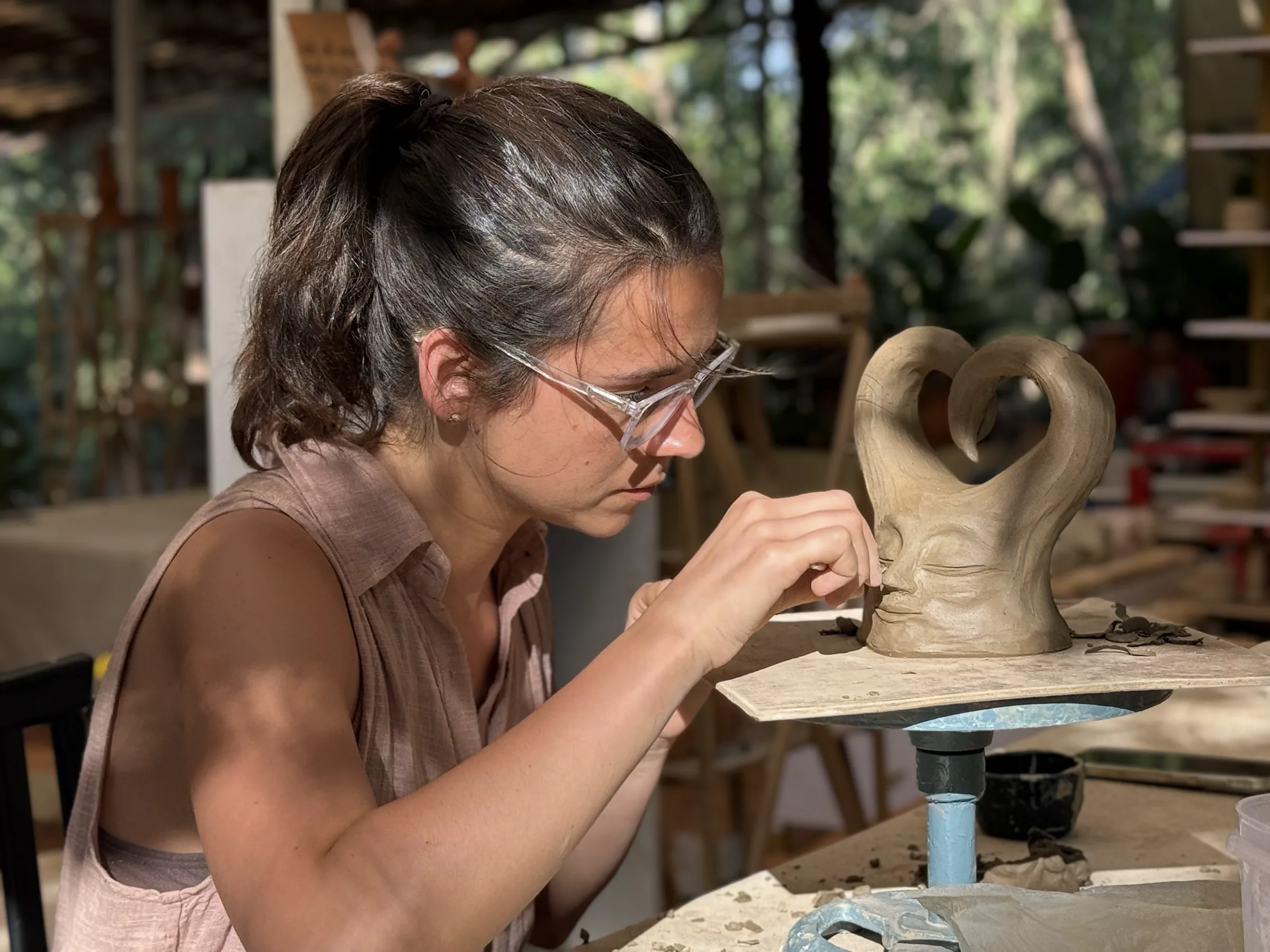 Participant refining the surface of a tall hand-built ceramic vase during the Sculpt & Shape workshop in Goa.