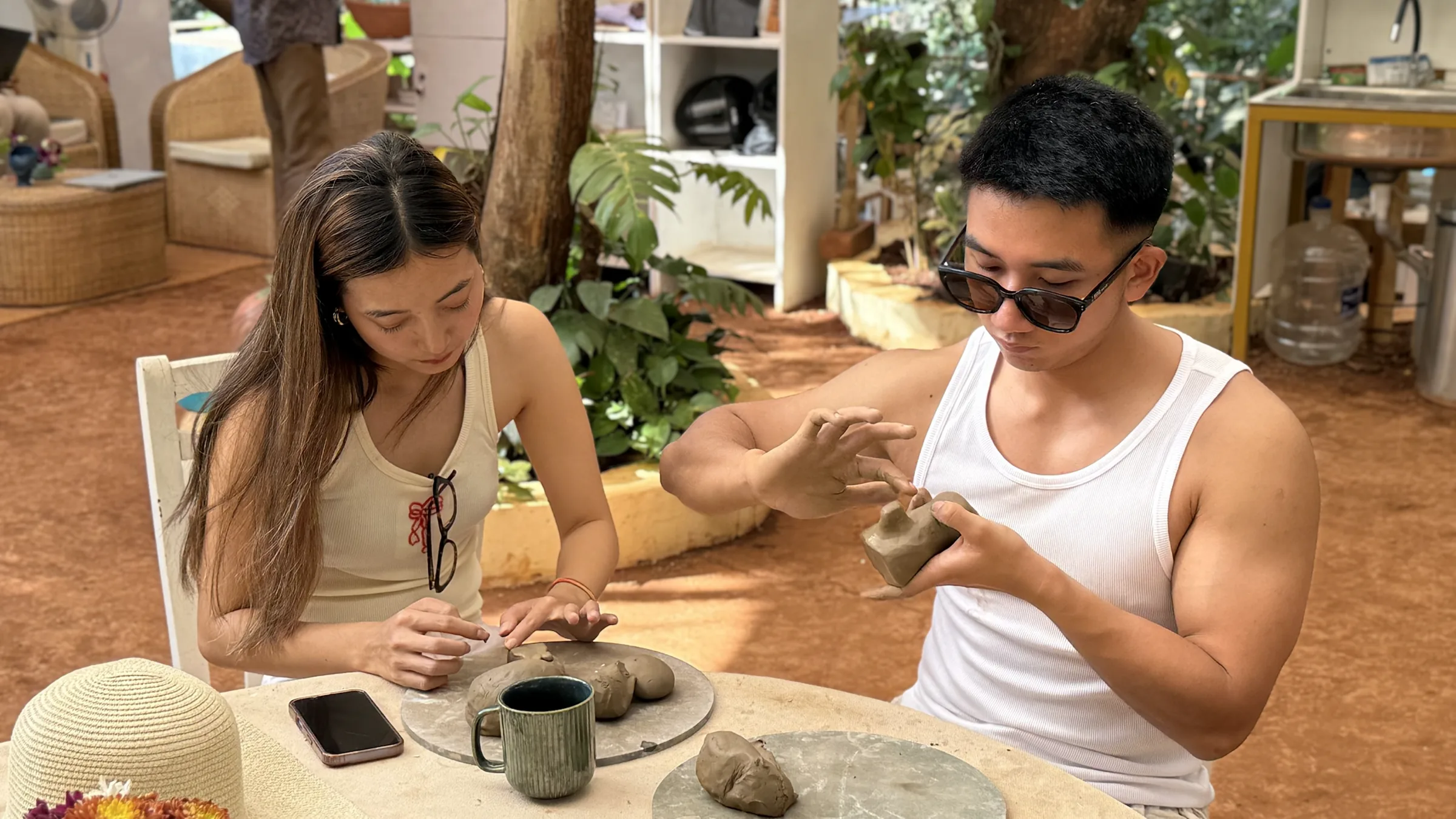 Two participants shaping hand-built clay pieces together during the Sculpt & Shape workshop at Dharamkot Studio in Goa.