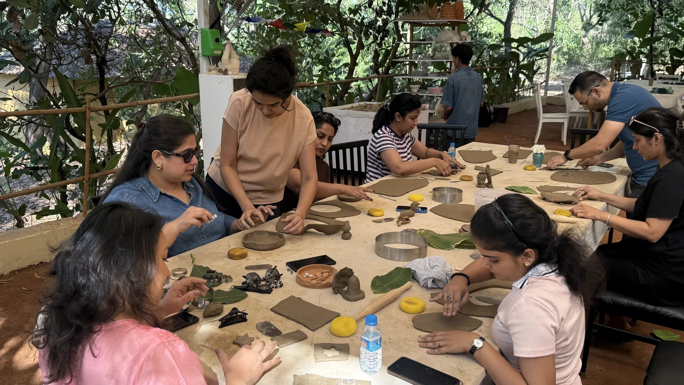 Overhead view of participants shaping slab-built pottery and small sculptural forms during a Goa handbuilding session.