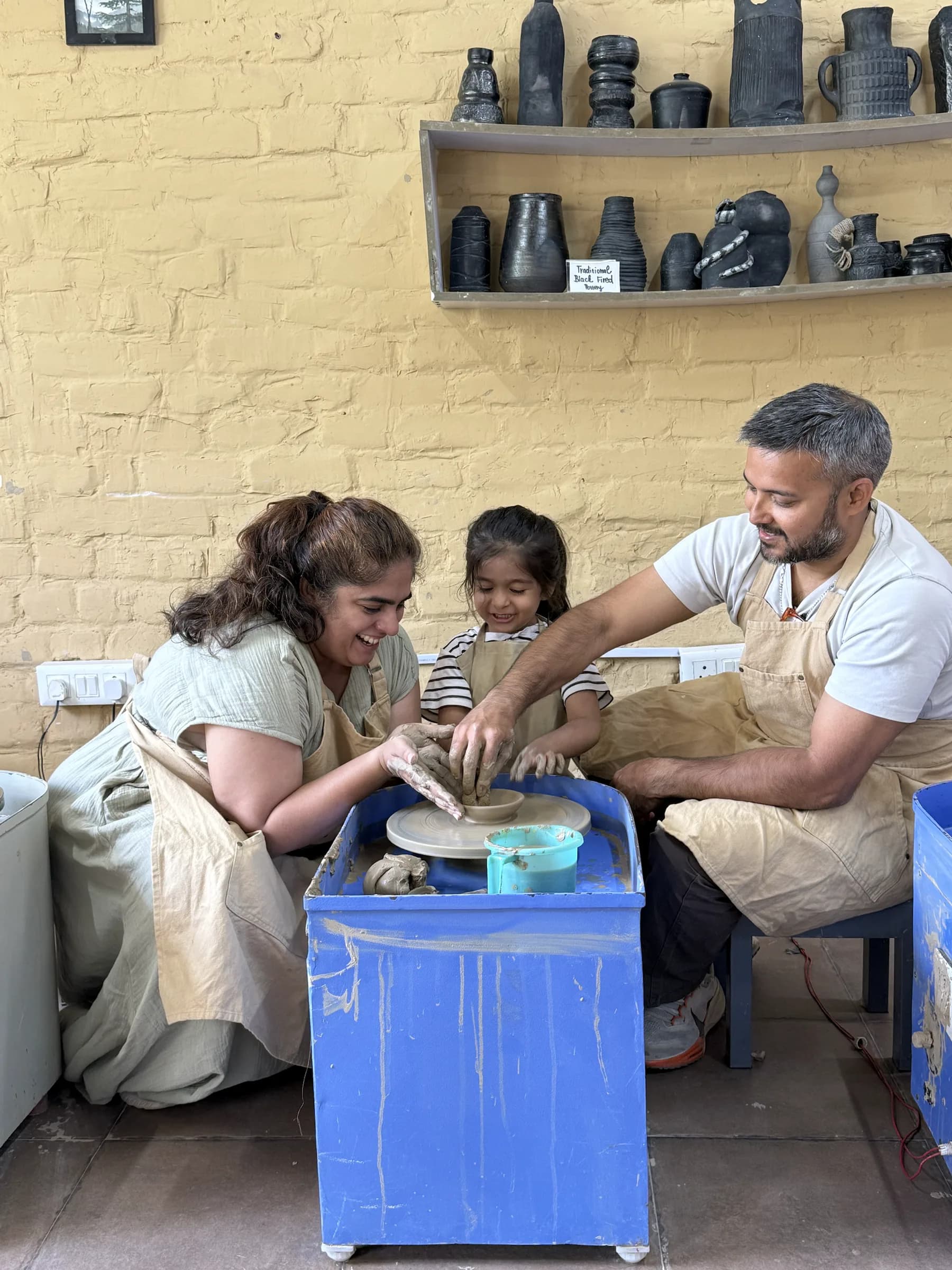 A family enjoying a guided pottery wheel moment during the Kids and Parents workshop.
