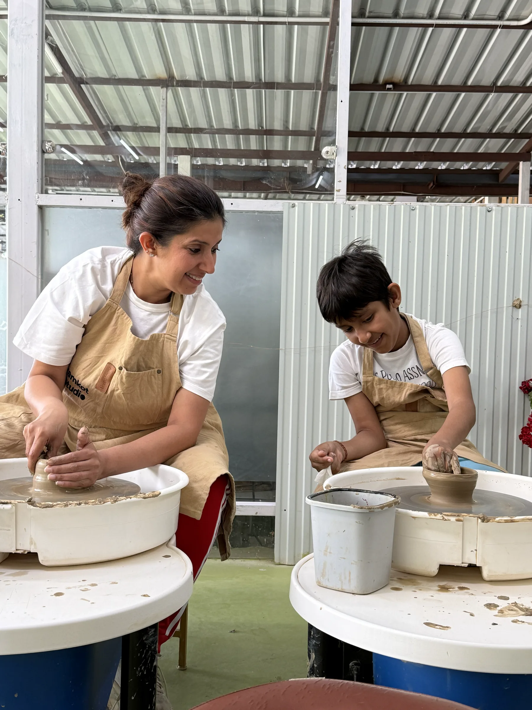Instructor helping a child shape clay on the pottery wheel during the Himachal Kids and Parents workshop.