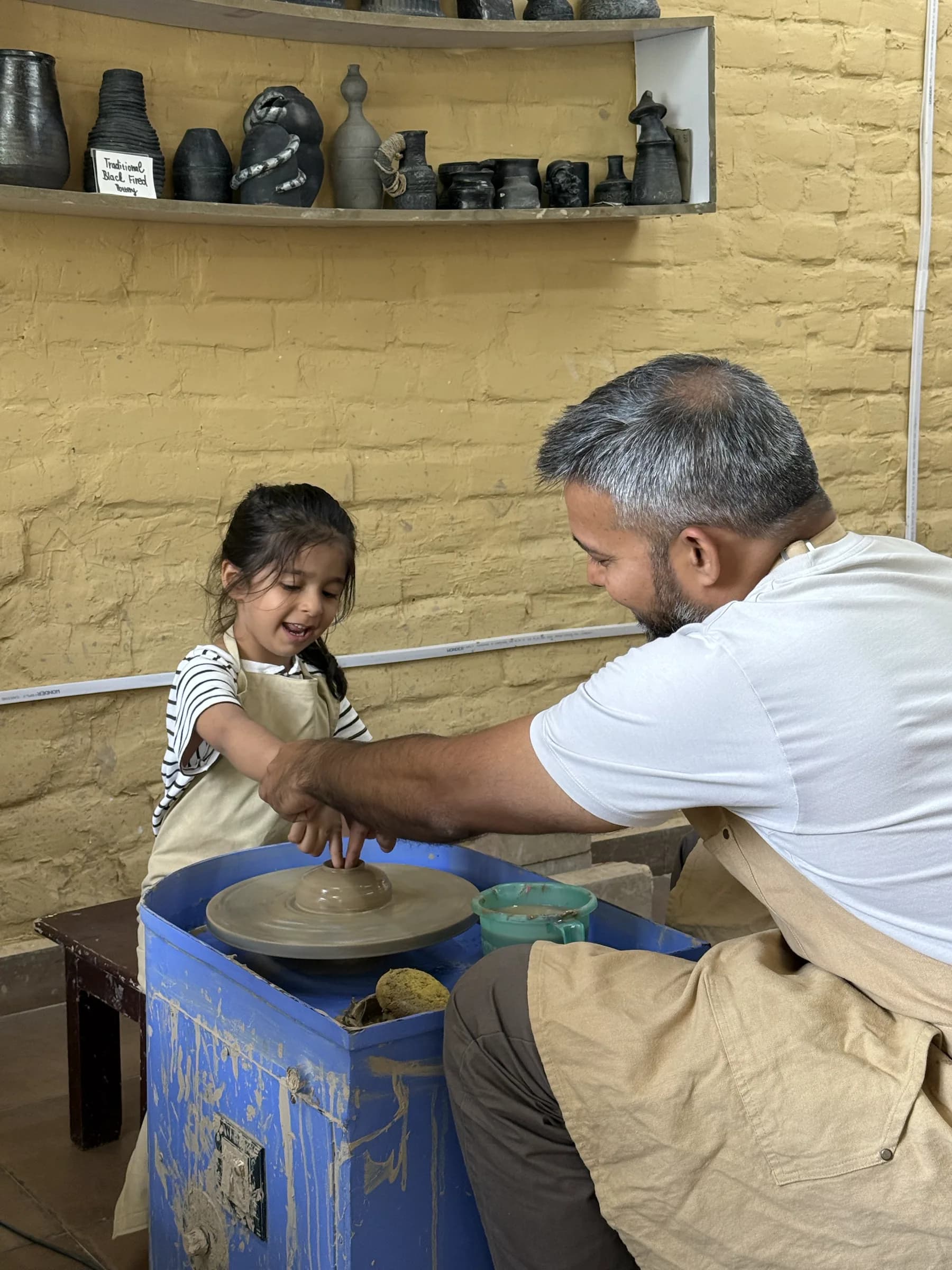 A parent guiding a child at the pottery wheel during the Himachal Kids and Parents workshop at Dharamkot Studio.