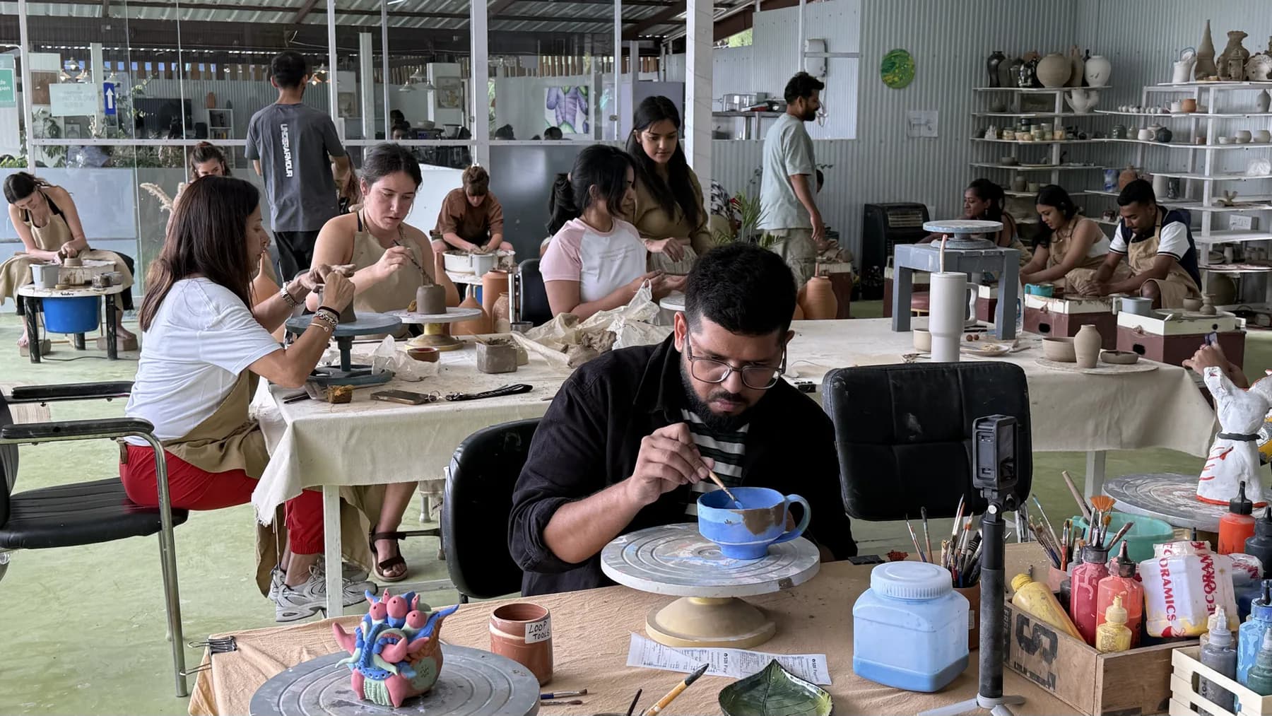 Open studio tables with participants, tools, and clay during the Himachal Open Clay Session.