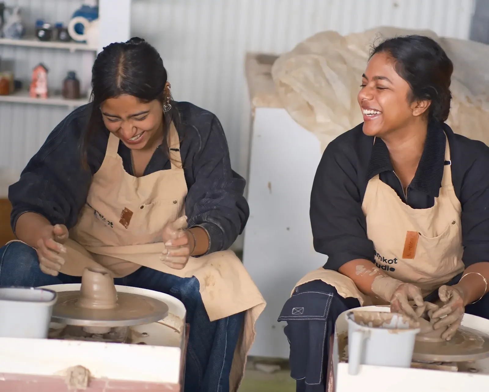 Smiling participants enjoying a pottery wheel experience at Dharamkot Studio in Himachal Pradesh.