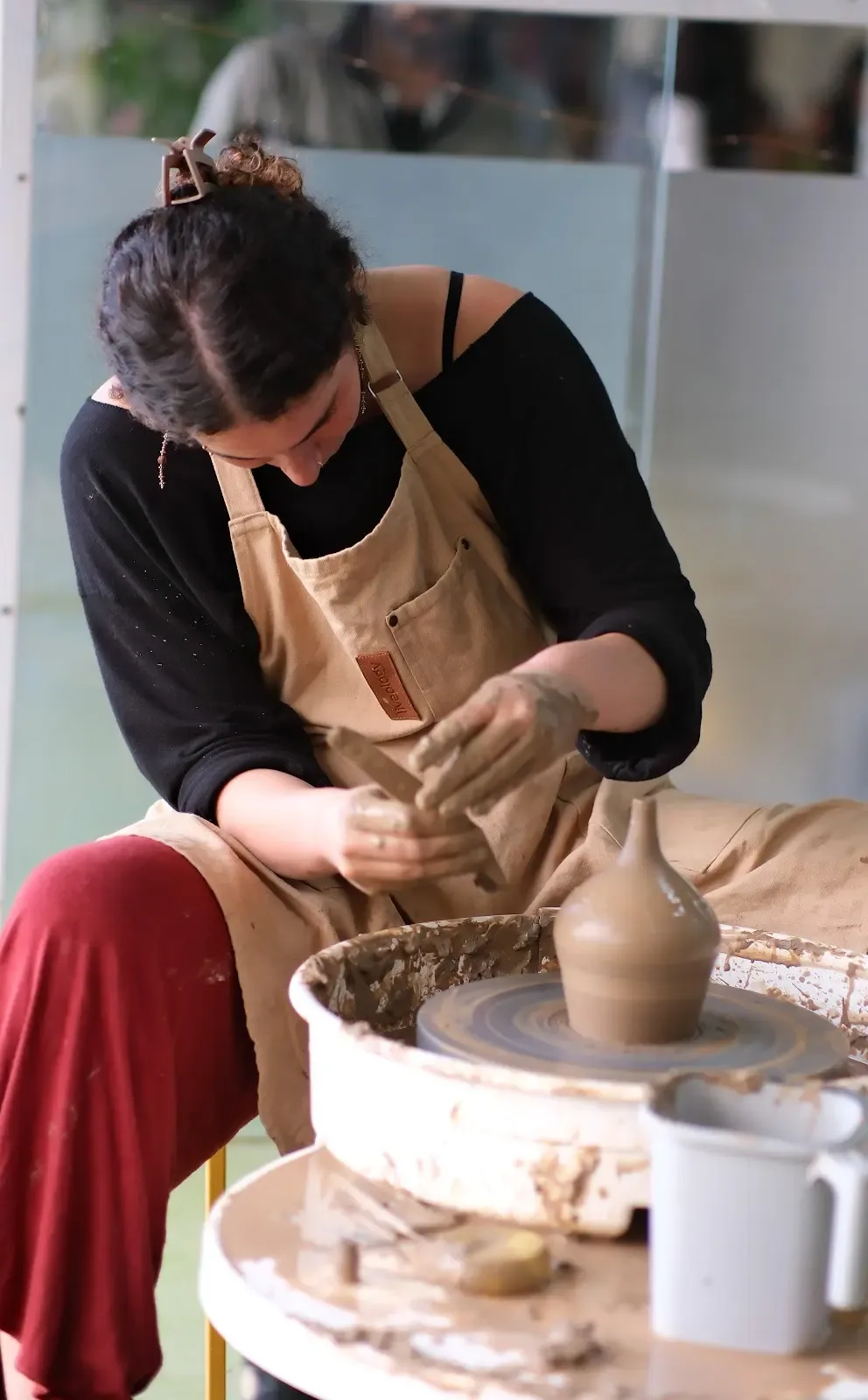 Participant shaping a tall clay vessel on the pottery wheel at Dharamkot Studio Himachal Pradesh.