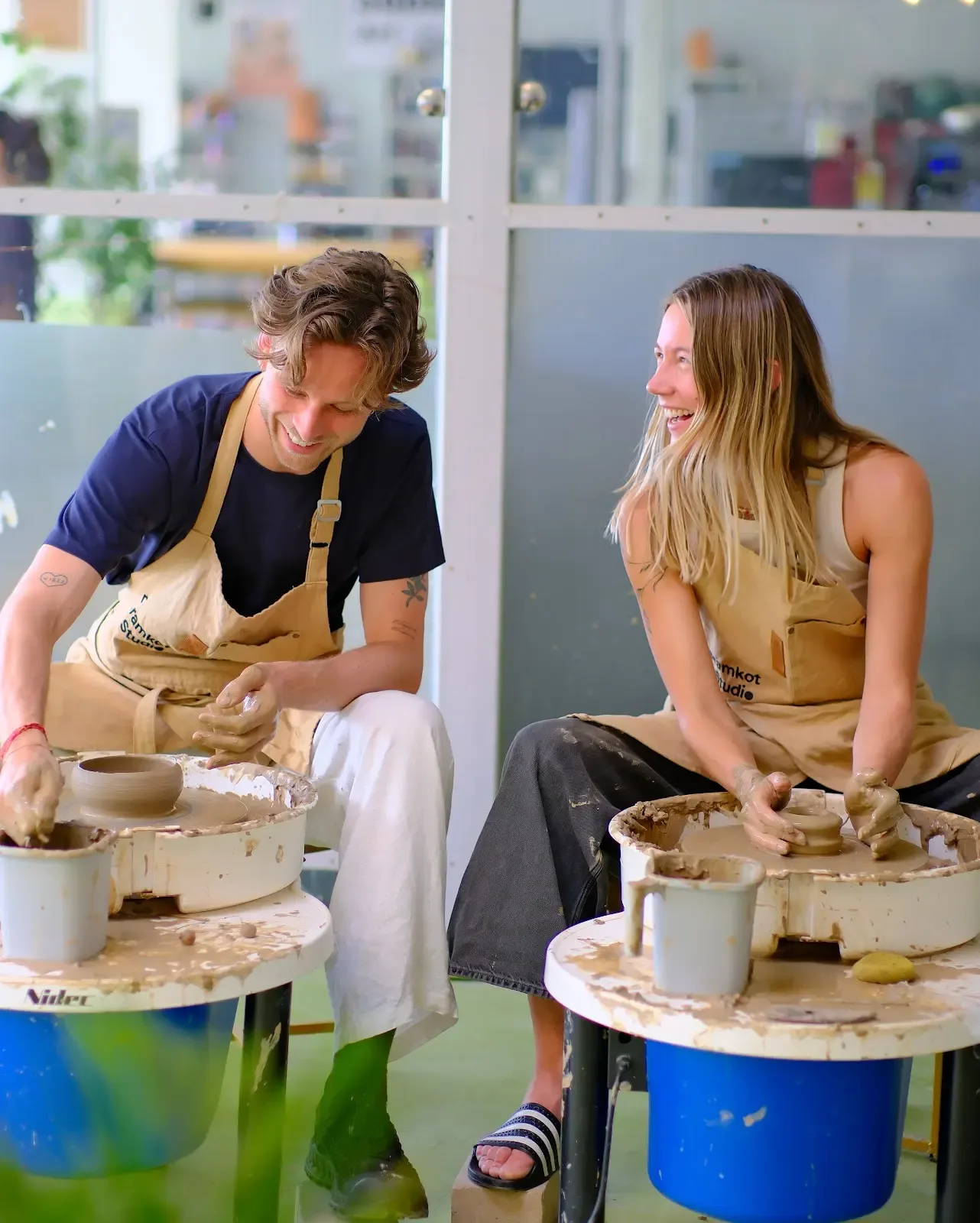 Two participants practicing pottery wheel throwing during the Himachal workshop at Dharamkot Studio.