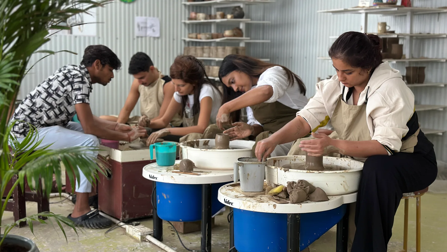 Students practicing pottery wheel forms together at Dharamkot Studio in Himachal Pradesh.