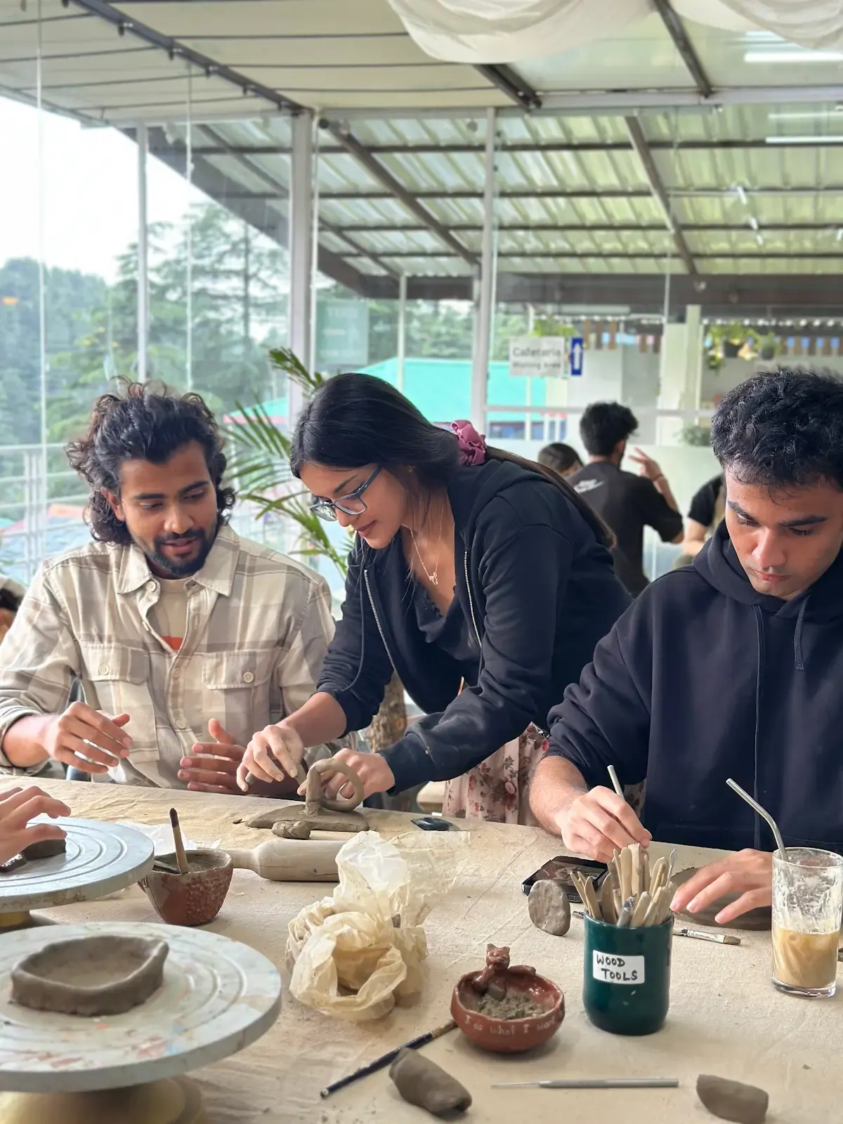 Participants shaping clay together around a shared handbuilding table at Dharamkot Studio Himachal Pradesh.