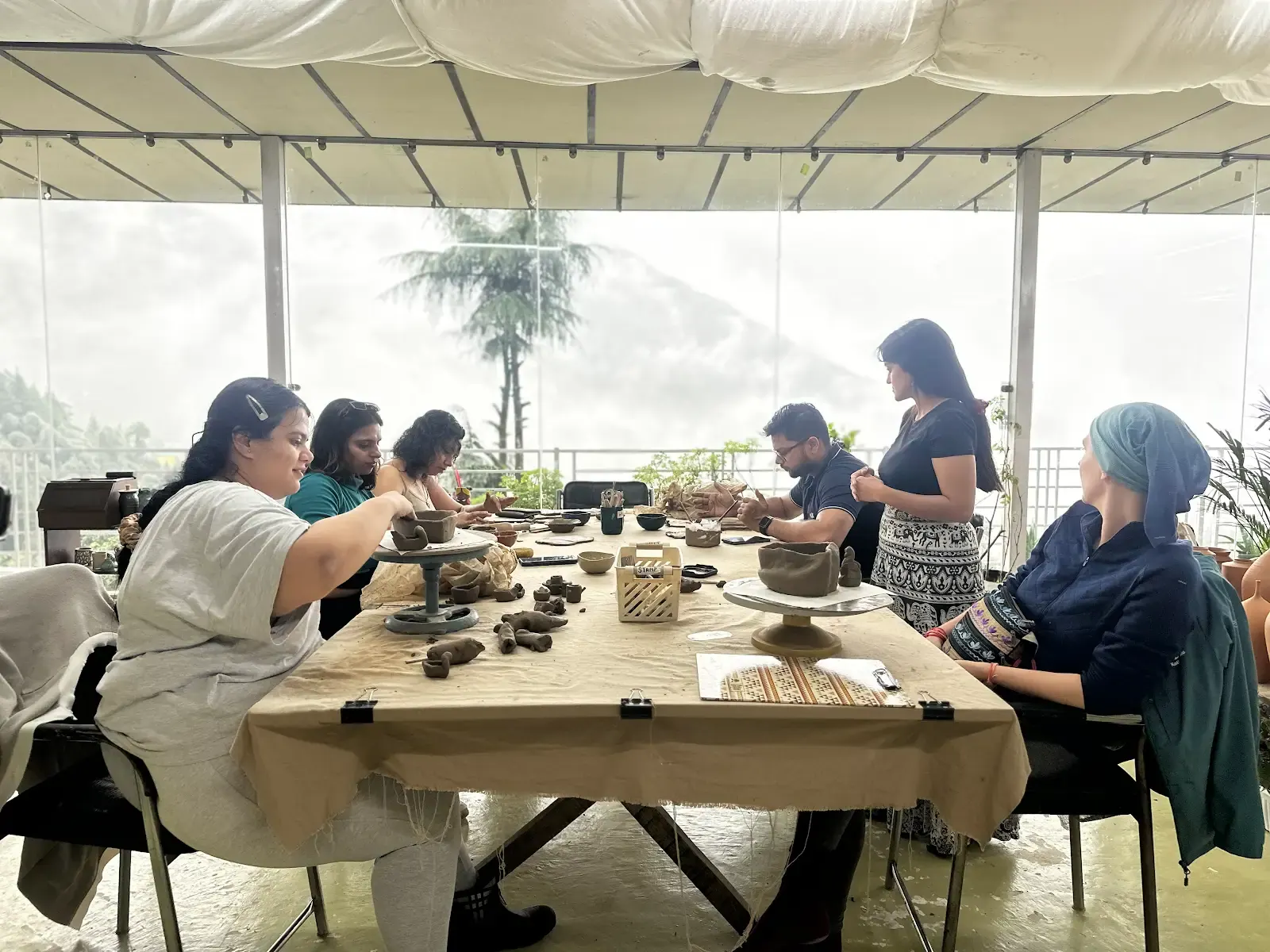 Open-air handbuilding session with participants making clay pieces in the Himachal mountain studio.