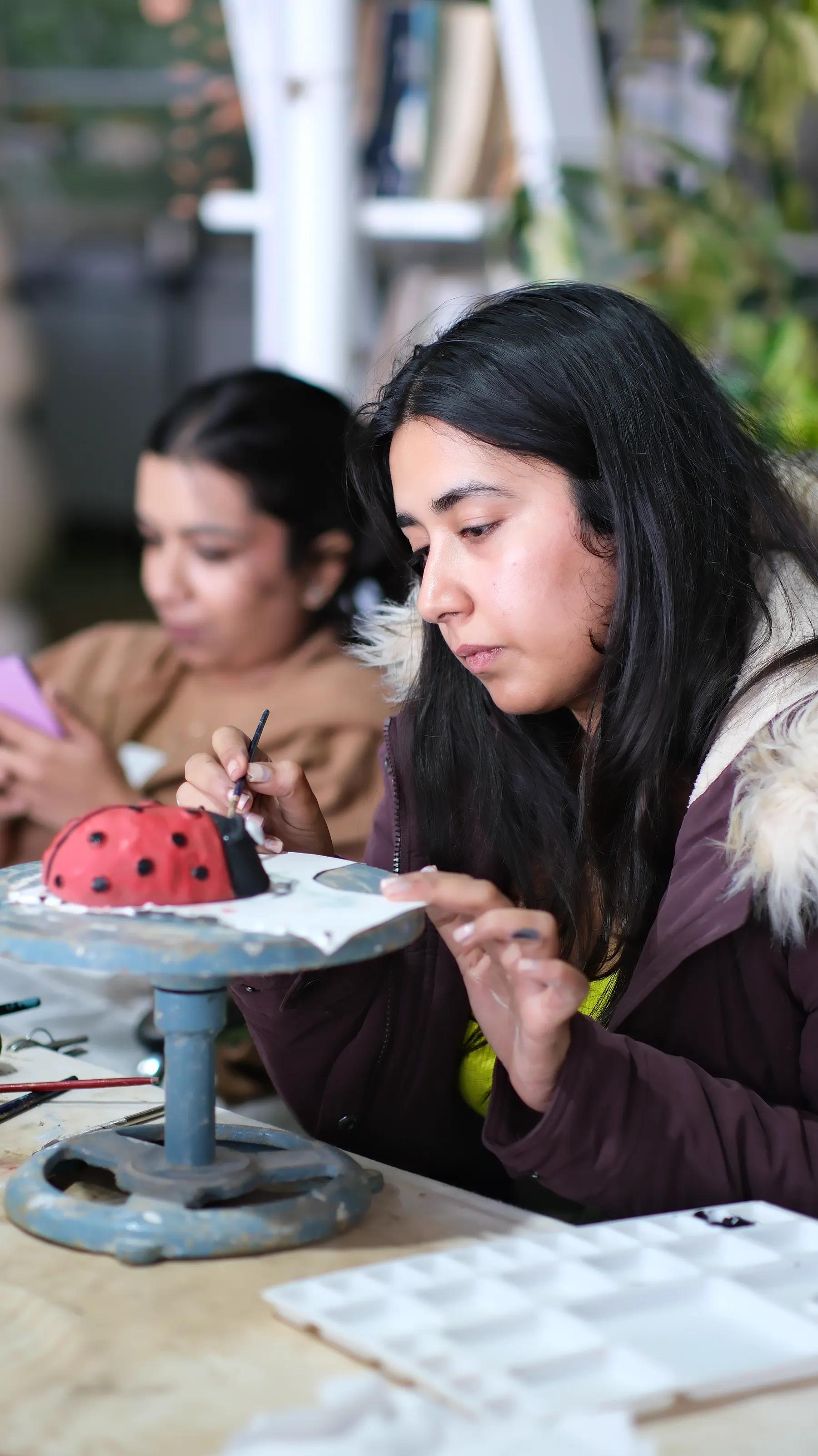 Participant painting a hand-built clay form during a Sculpt & Shape workshop in Dharamkot, Himachal Pradesh.