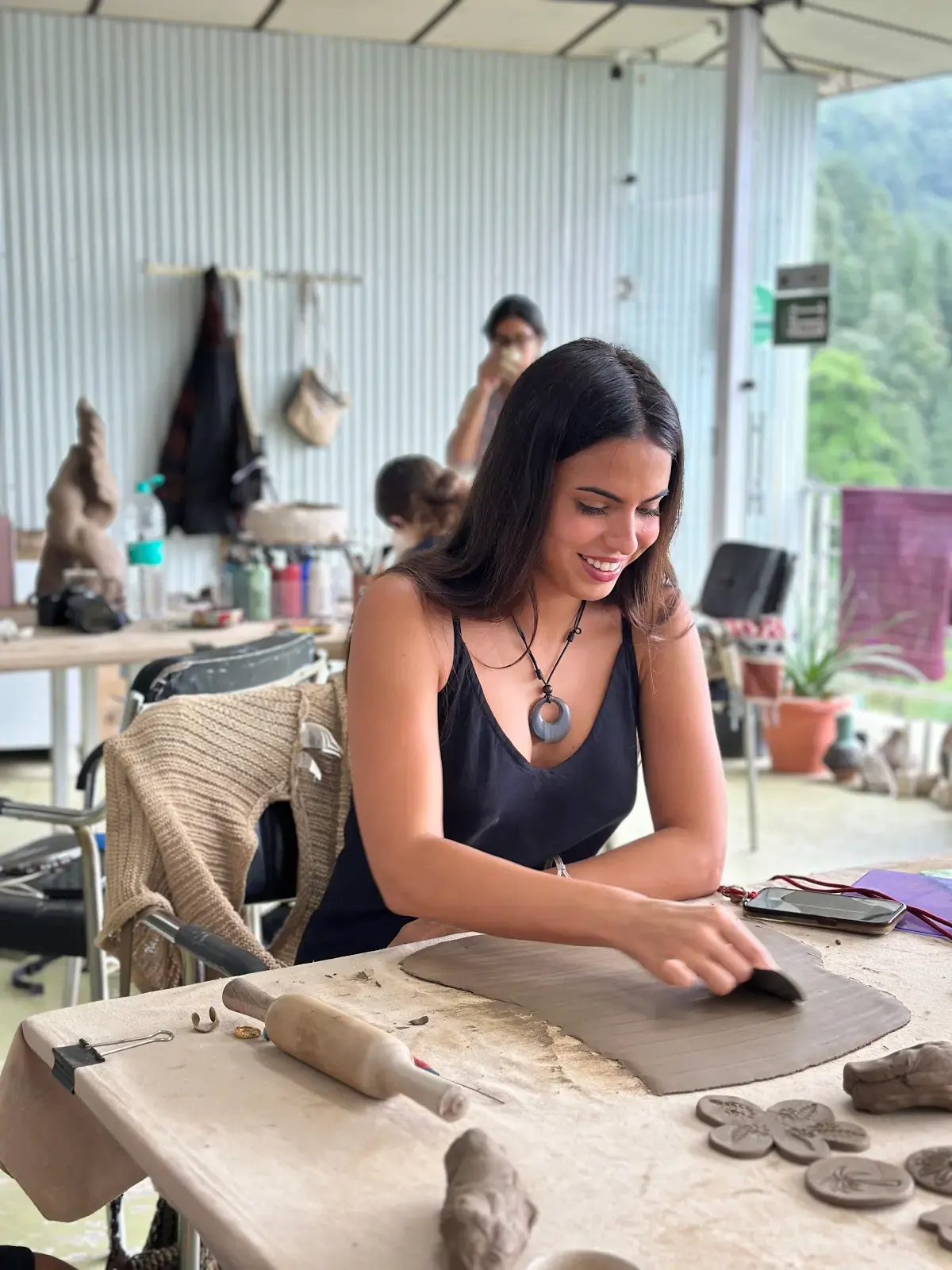 Participant arranging clay slabs and small hand-built forms during the Himachal Sculpt & Shape workshop.