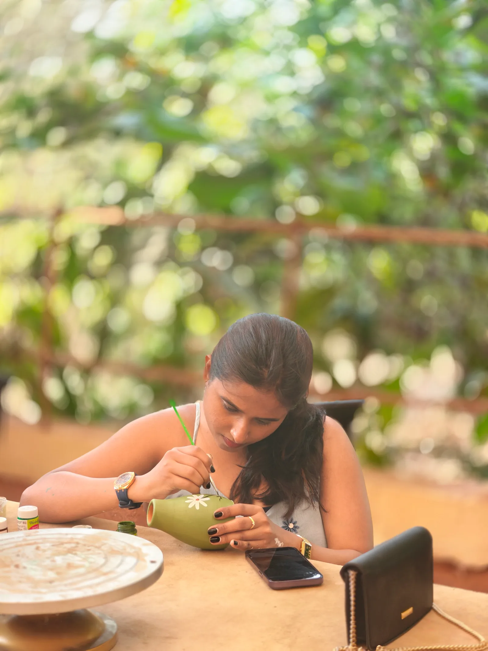 Paint on Pottery workshop participant decorating a ceramic vase with acrylic colours at Dharamkot Studio in Himachal Pradesh.