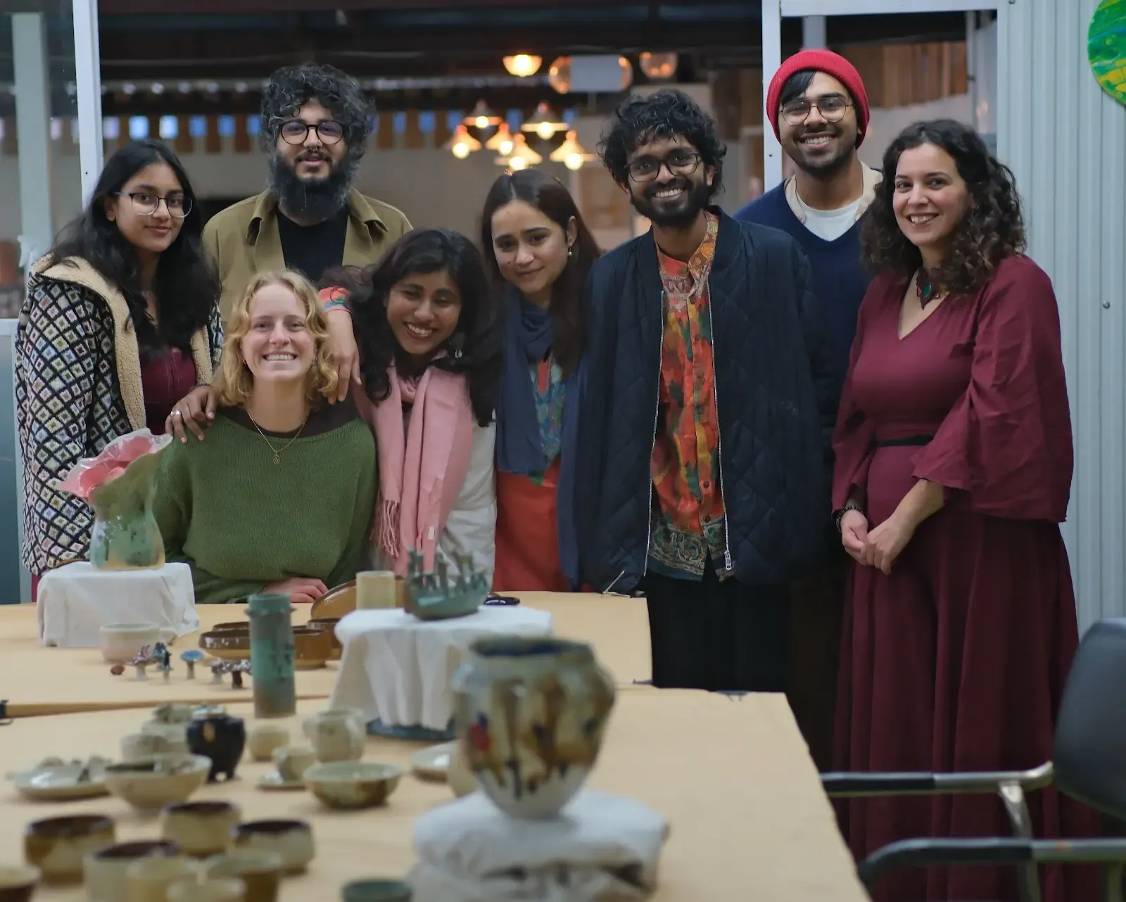 Pottery course students gathered around finished ceramic vessels at Dharamkot Studio.