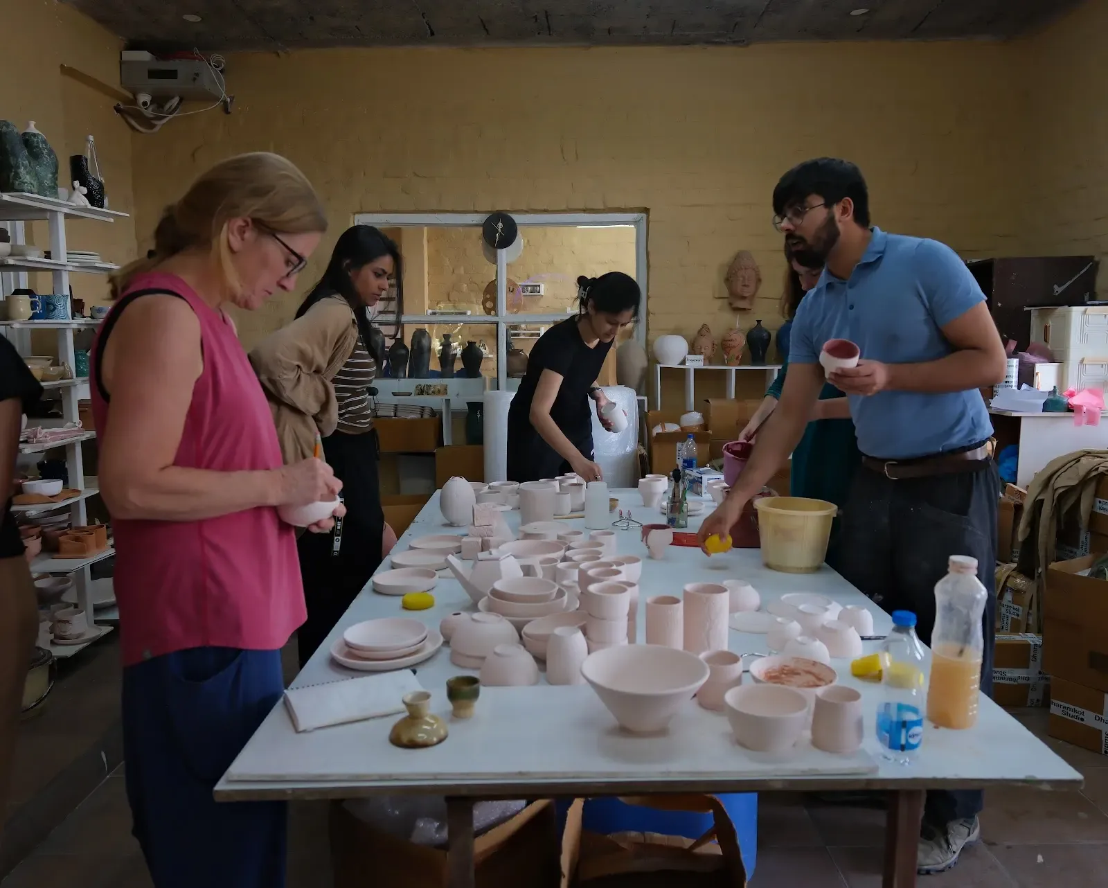 Pottery school students learning together in the Dharamkot Studio classroom and worktable area.