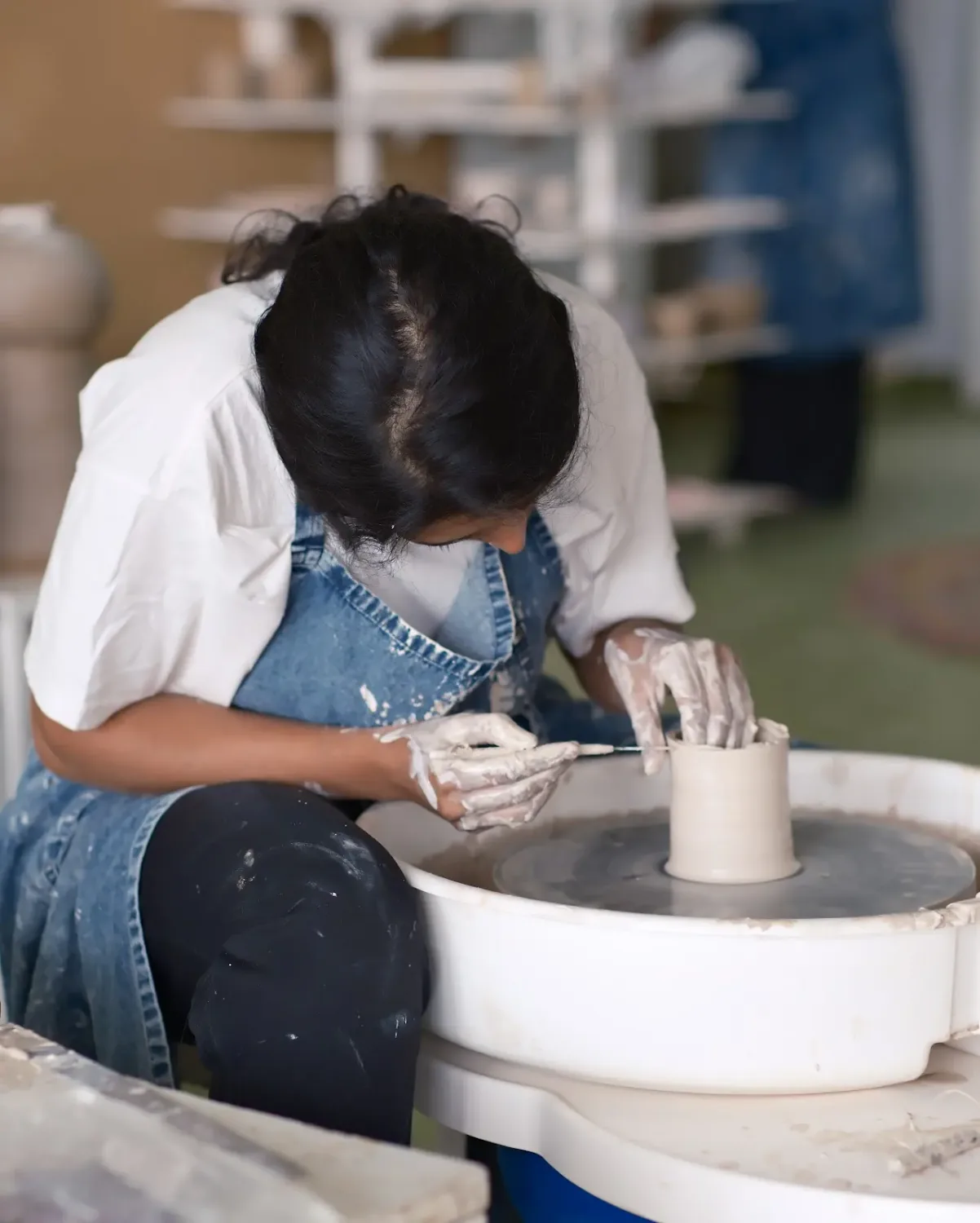 Student refining a ceramic form during a Dharamkot Studio pottery course.