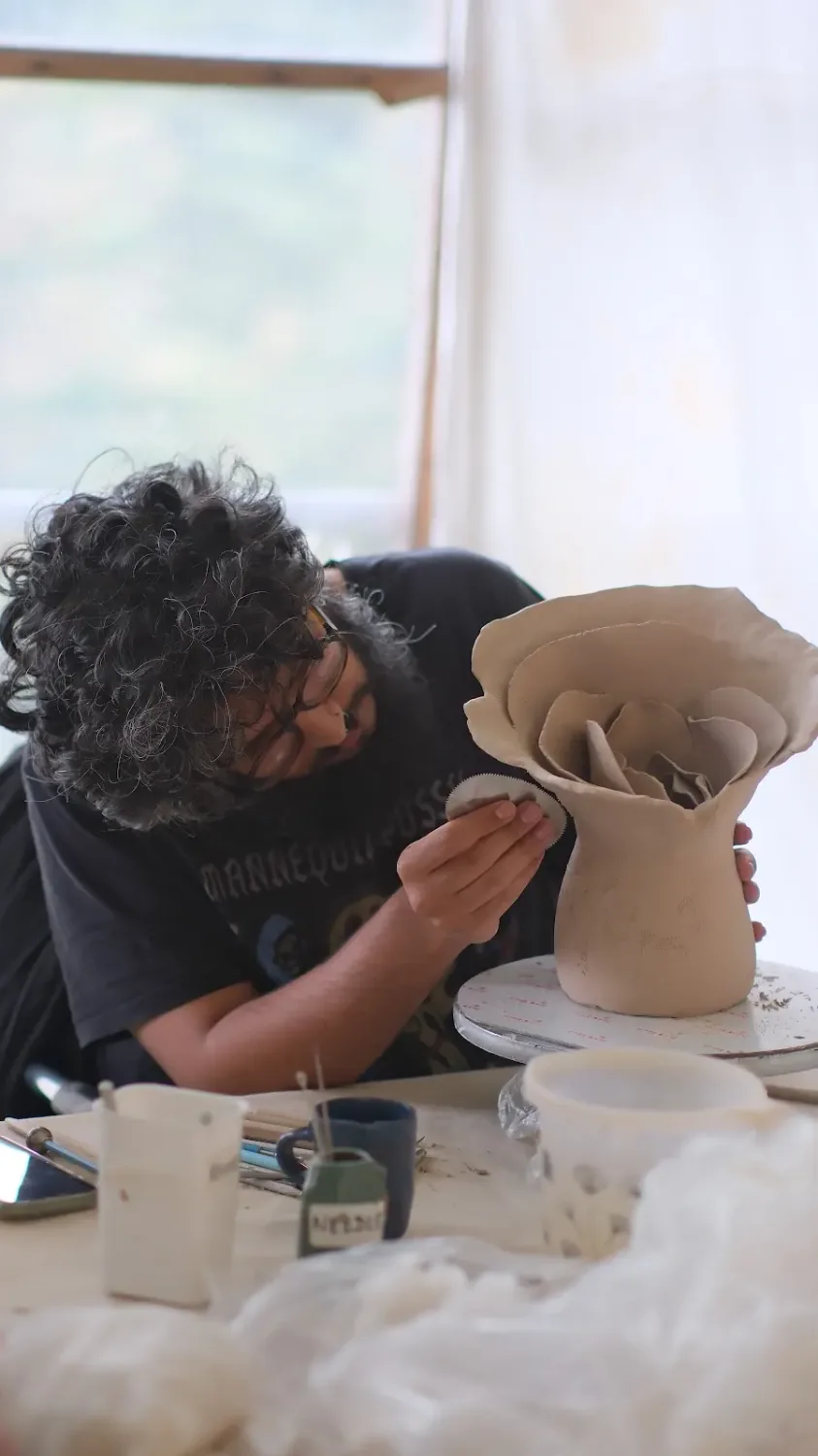 Pottery school student refining a large clay form during an advanced practice session.