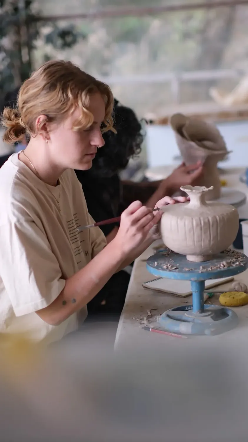 Student trimming a ceramic vessel on the pottery wheel during Dharamkot Studio's school course.