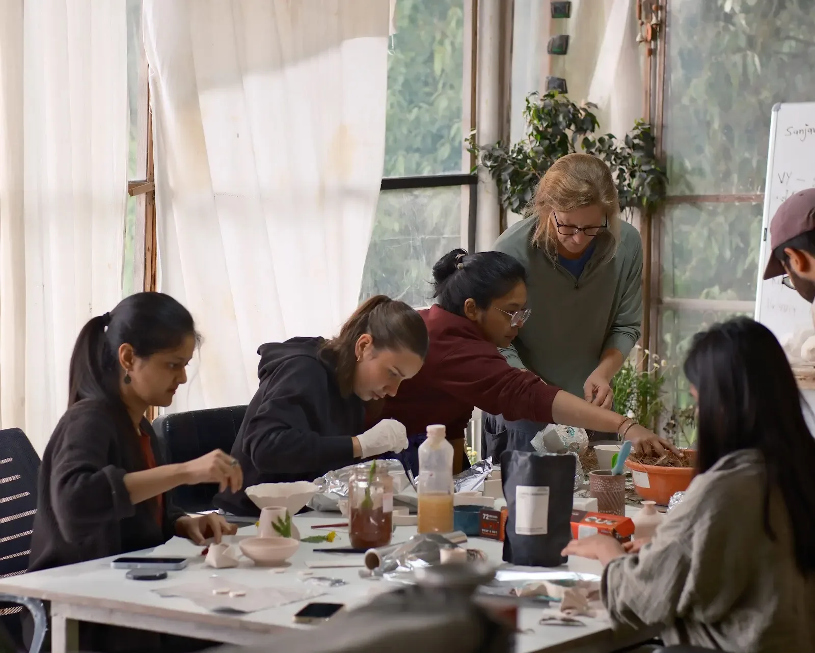 Students handbuilding ceramic forms around a studio table during the five-week pottery course.